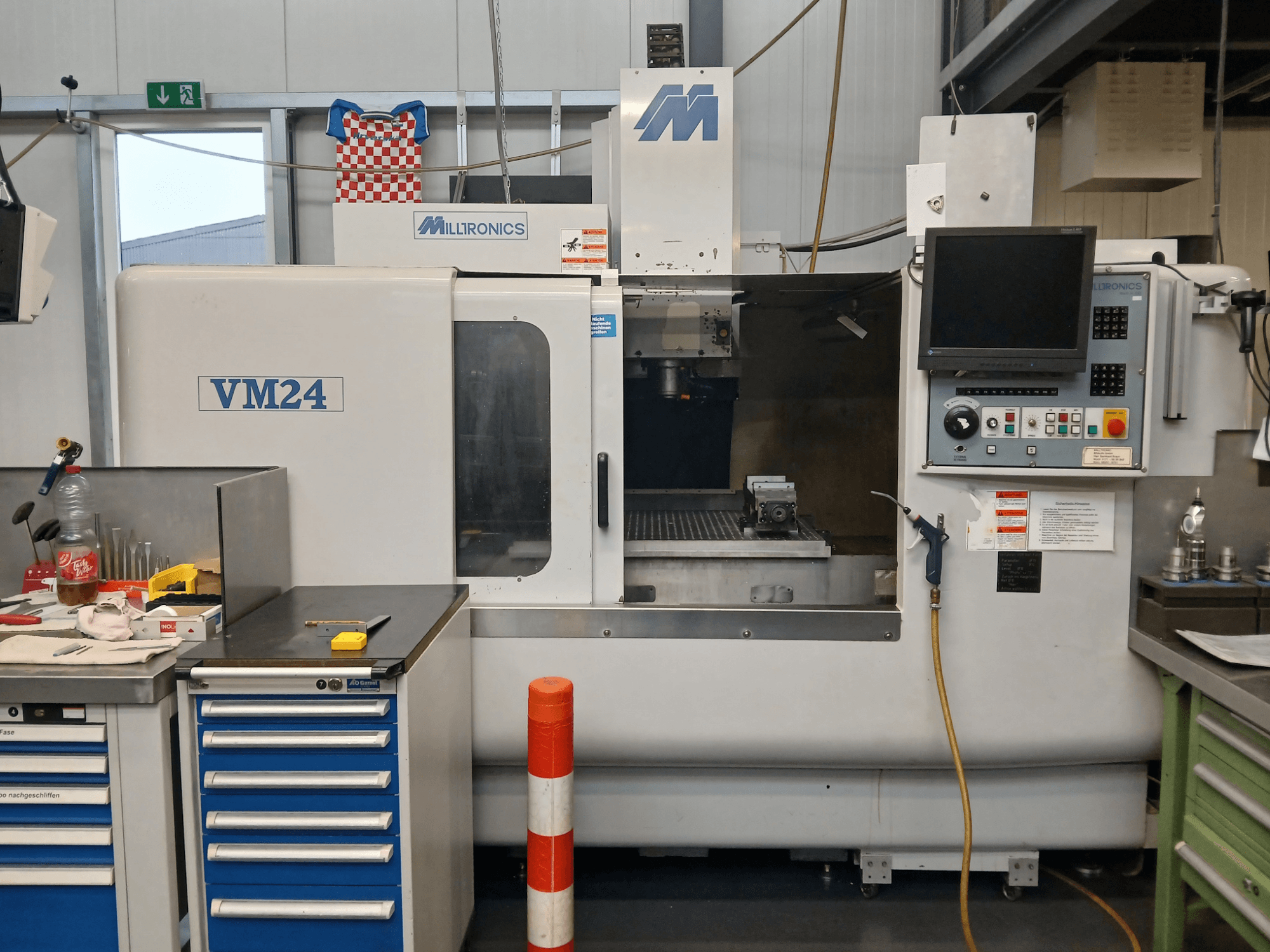 Milltronics VM24 CNC marógép szemből, a vezérlőpanel, a szerszámtároló és a munkaterület beállításával.