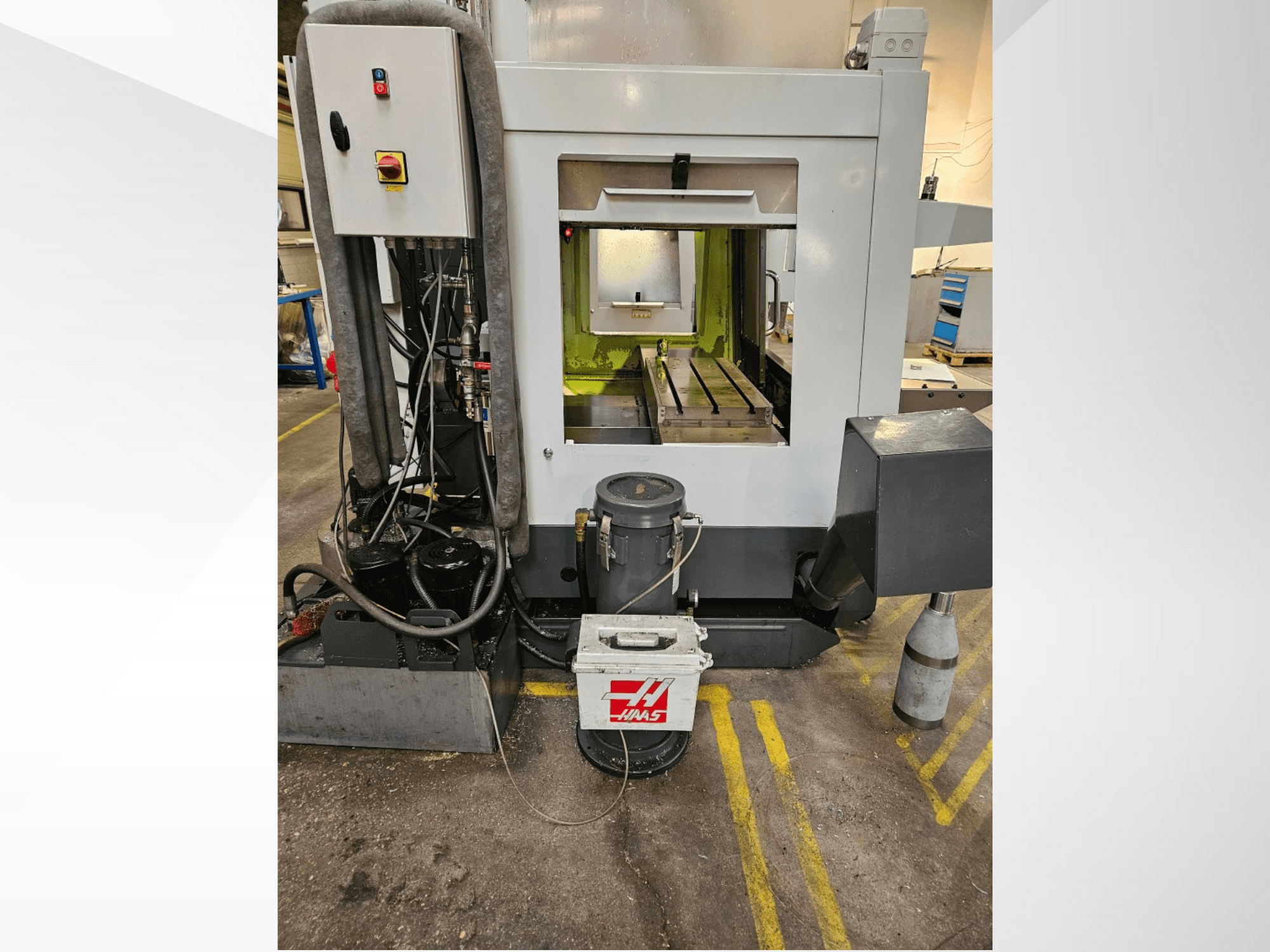 Haas CNC-gép elülső nézete a vezérlőpanel, a hűtőfolyadék-tartály és a megmunkált ágy bemutatásával.