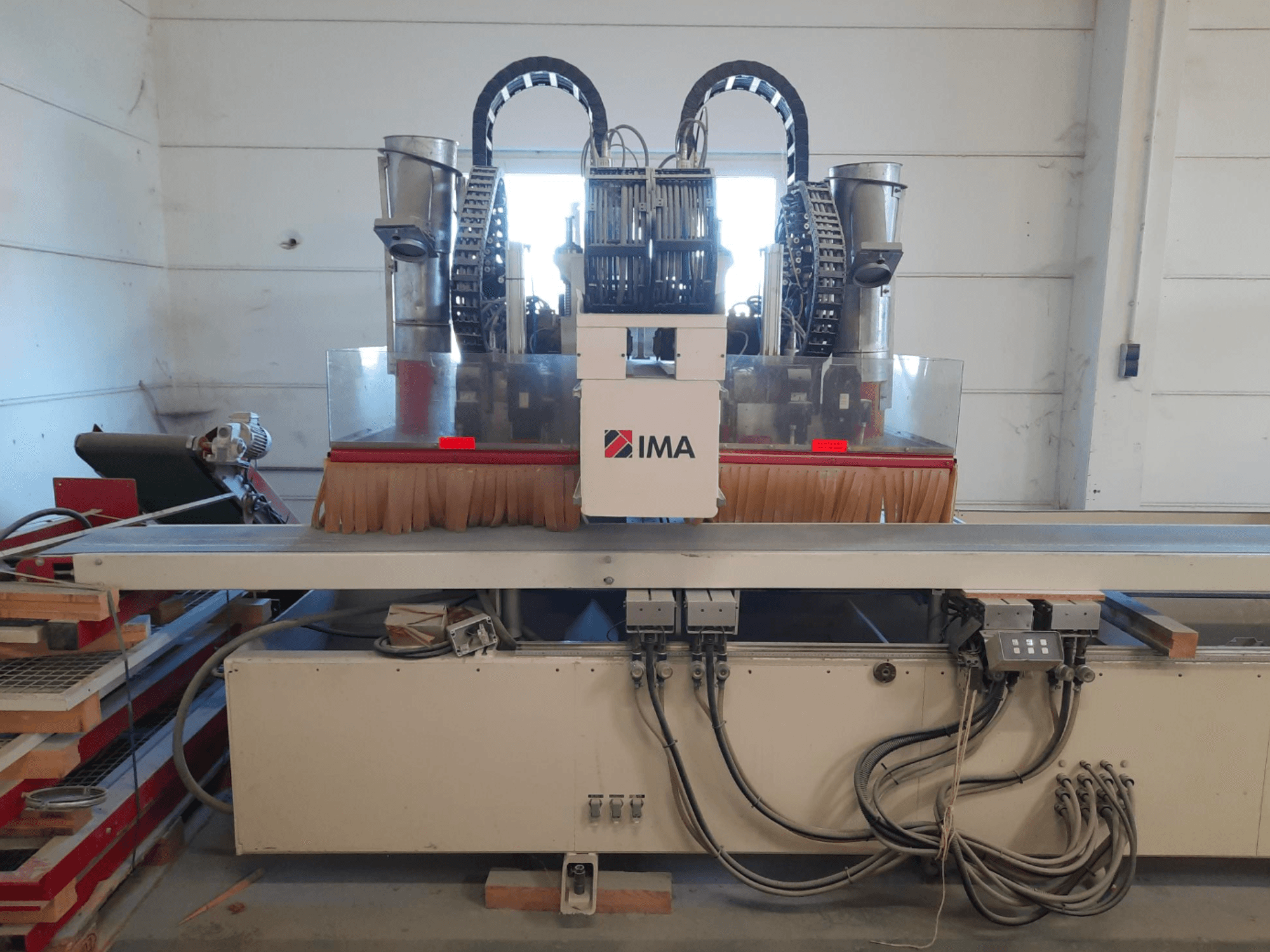 Az IMA BIMA 610 V CNC faipari megmunkáló központ elölnézete, kefékkel, vezérlőelemekkel és munkapaddal.