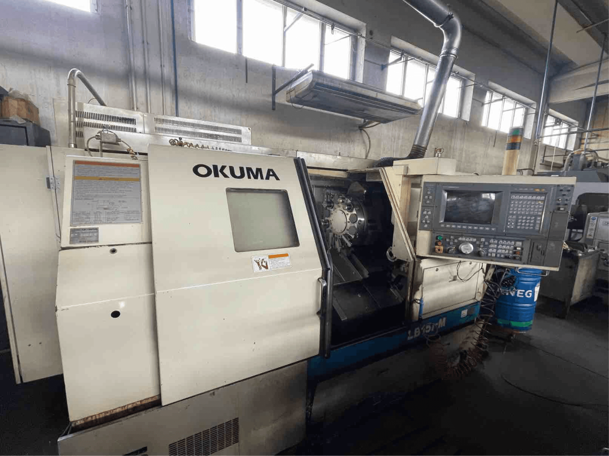 Okuma LB15i-M vízszintes esztergagép, elölnézet; vezérlőpanel és vágószerszám terület részletes kijelzőkkel.