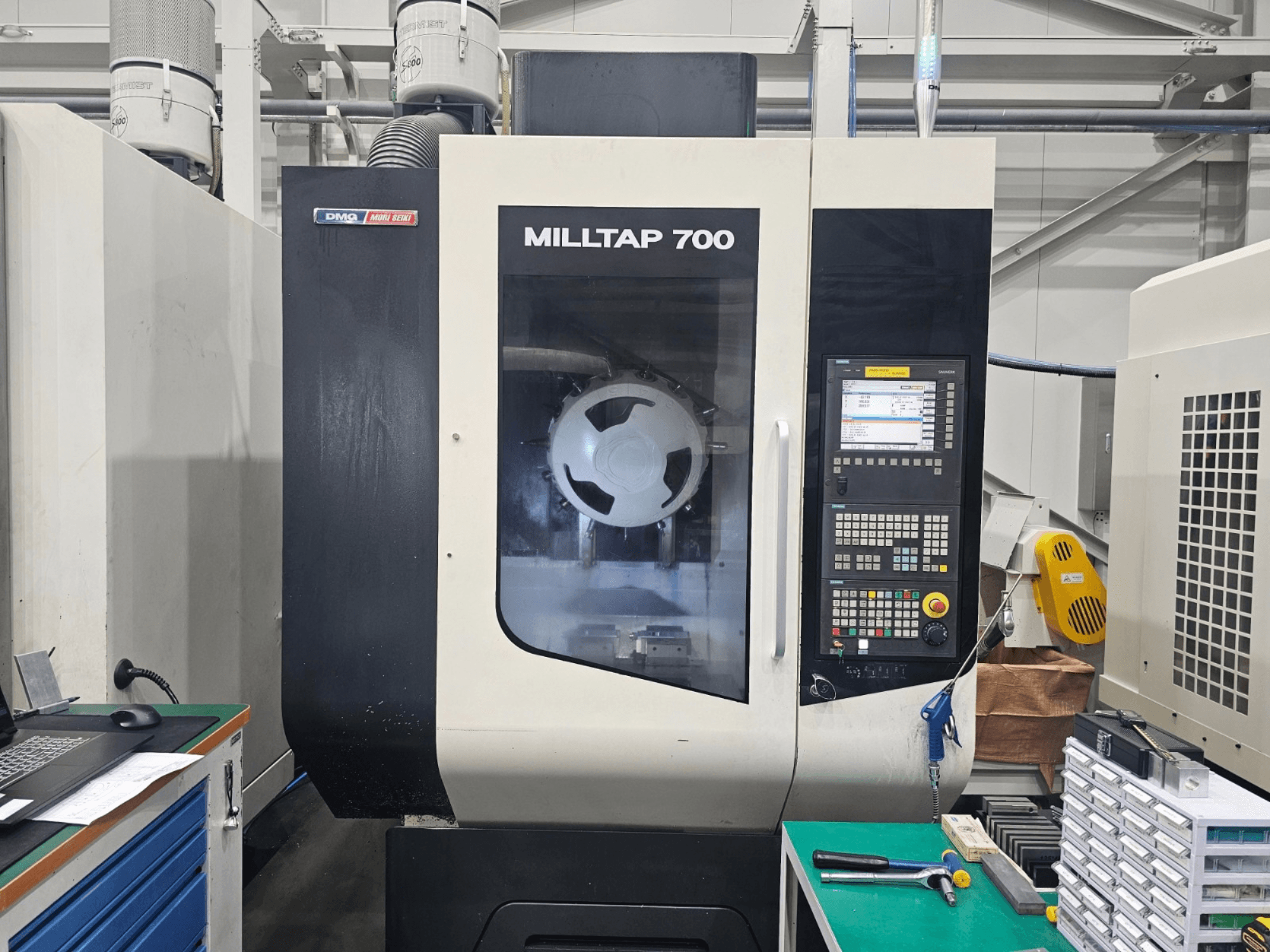 DMG MORI MILLTAP 700 függőleges megmunkáló központ, elölnézet, amelyen látható a vezérlőpanel, az orsó és a munkaterület részletei.