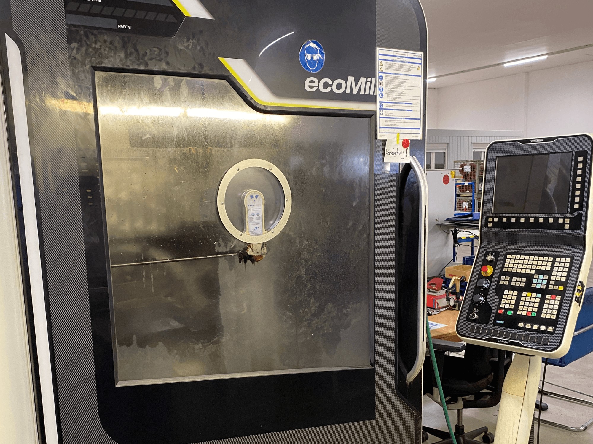 A DMG MU 70 ECO marógép elölnézete, jobbra a vezérlőpanellel és egy üvegpanellel, amelyen keresztül a belső alkatrészek láthatók.