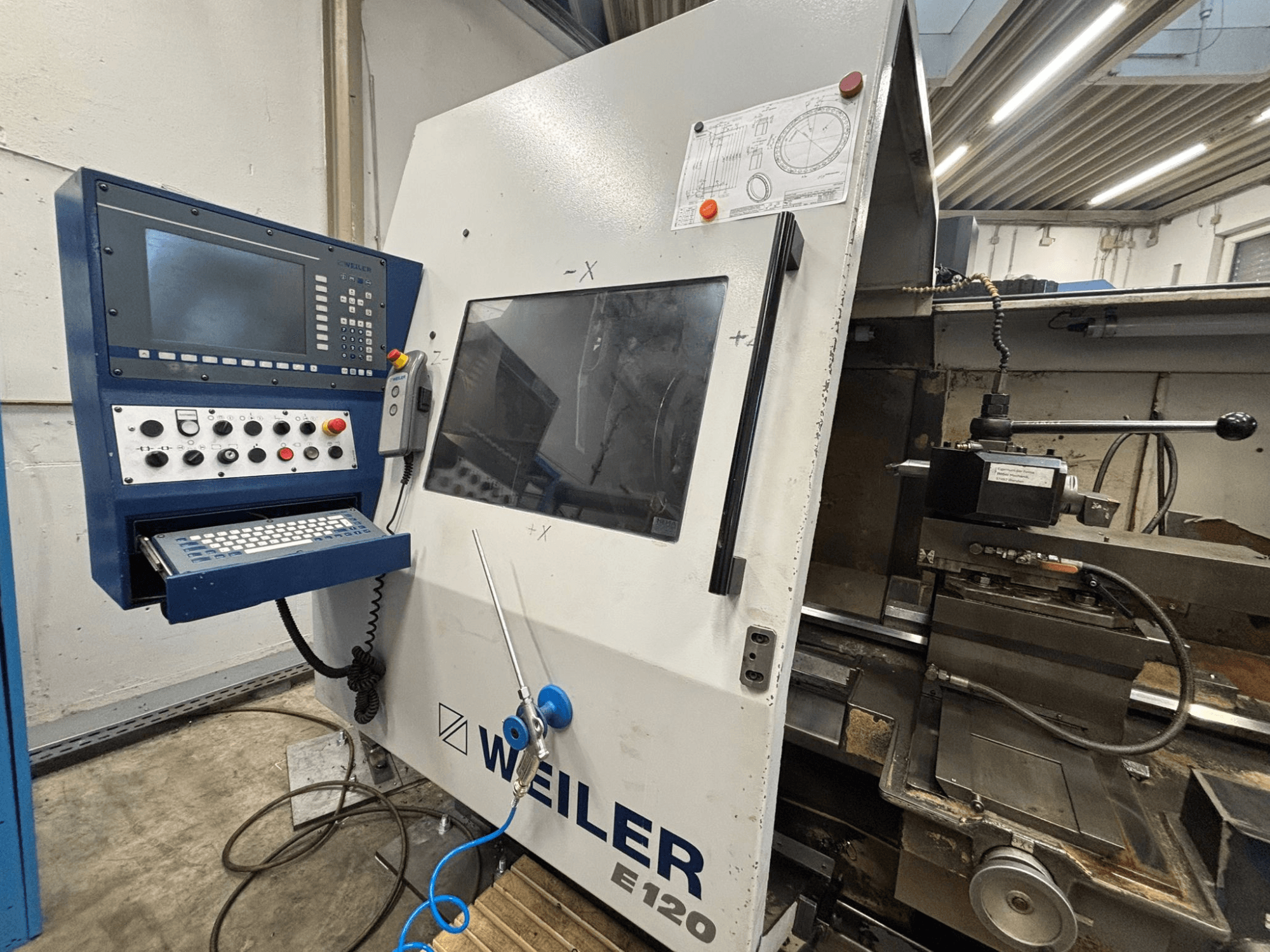 Weiler E-120 CNC gép vezérlőpanelje és kezelőfelülete, előlnézet a látható gombokkal, a kijelző képernyővel és a kezelőelemekkel.