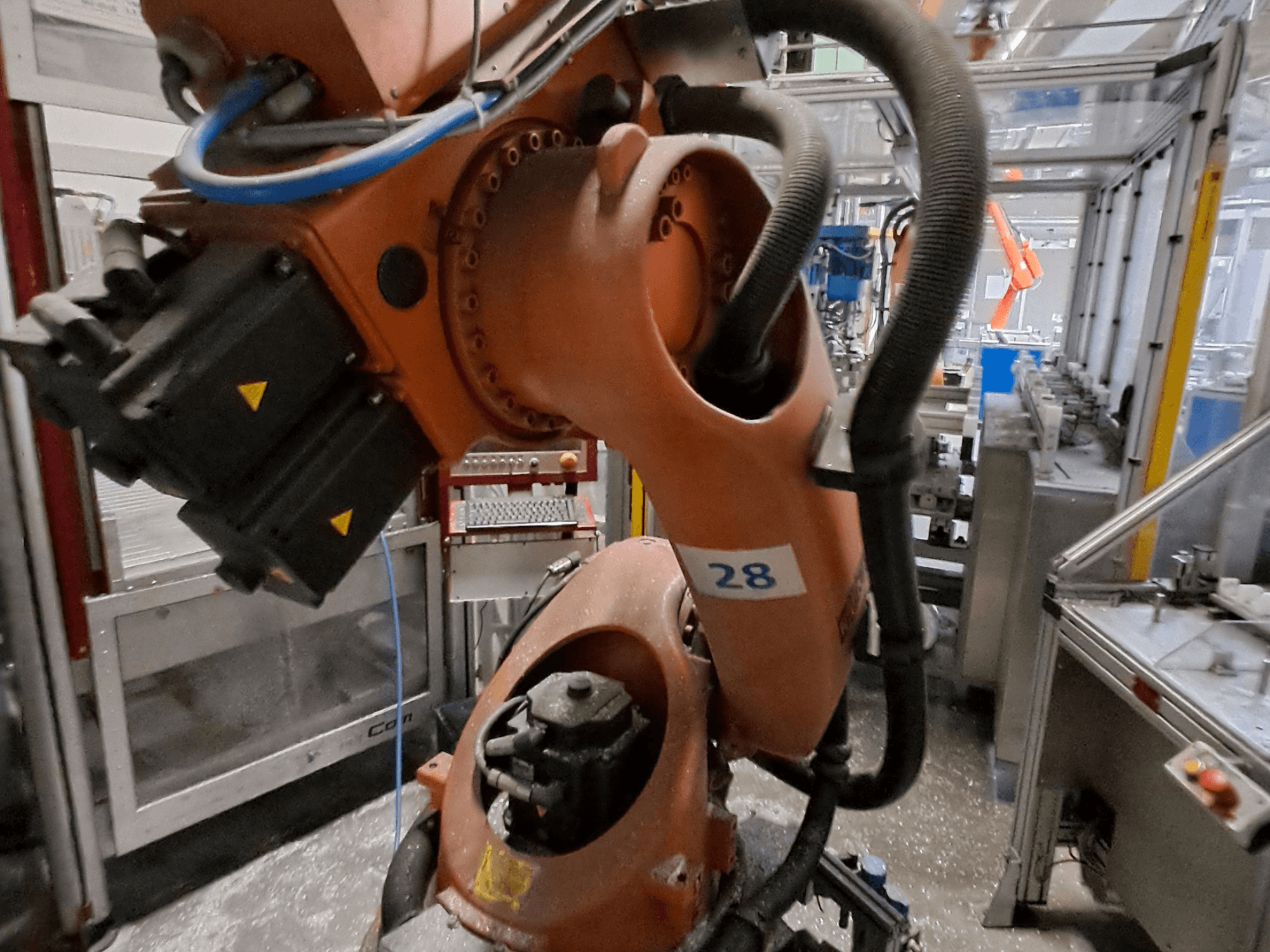 A KUKA KR30-3 robotkar közelképe: narancssárga test, 28-as számmal jelölve, oldalnézetből láthatók a motorok és a vezetékek.