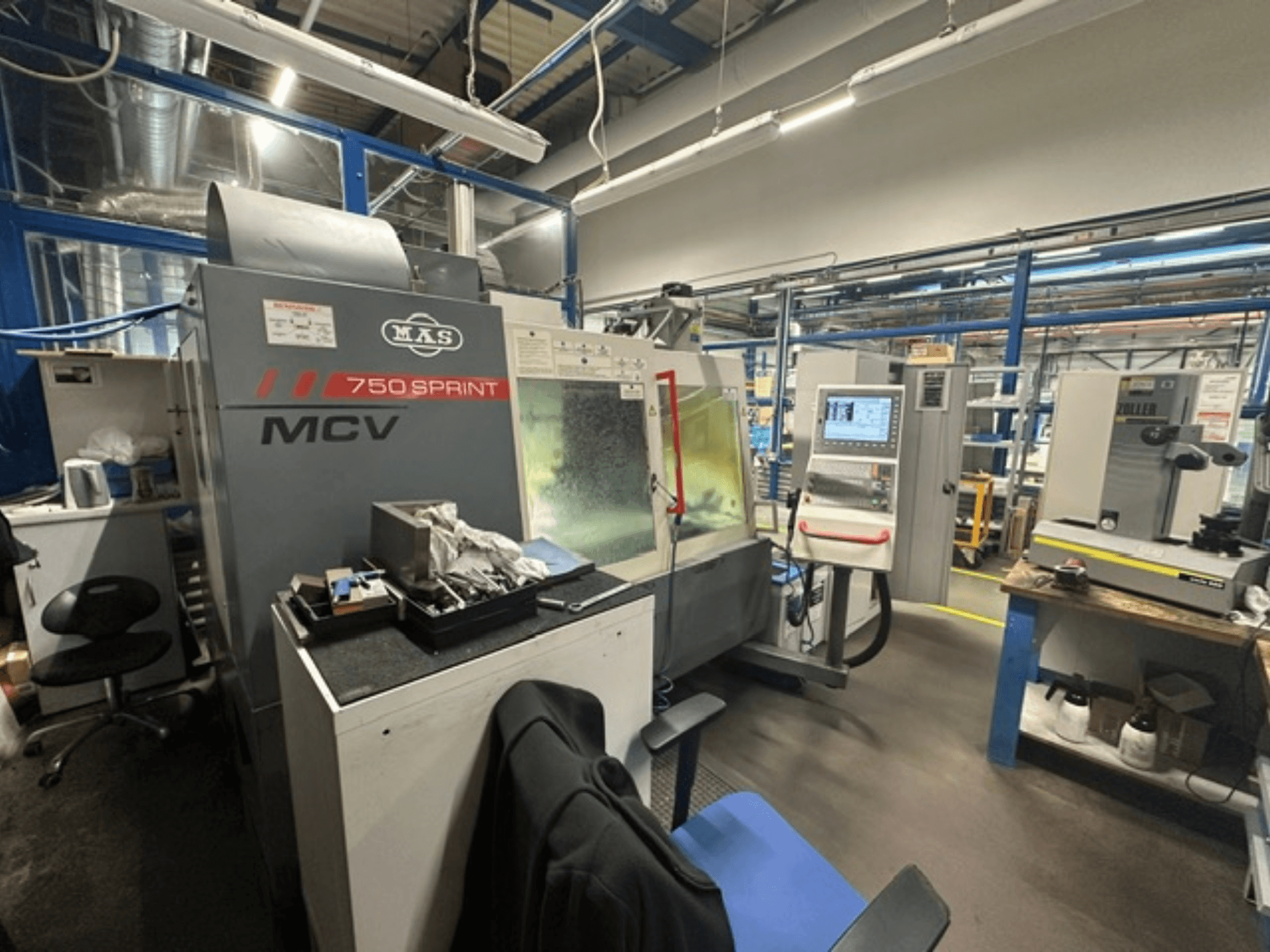 A KOVOSVIT MAS MCV 750 Sprint függőleges megmunkáló központ egy műhelyben, oldalnézetből látható a vezérlőpult és a munkaterület.