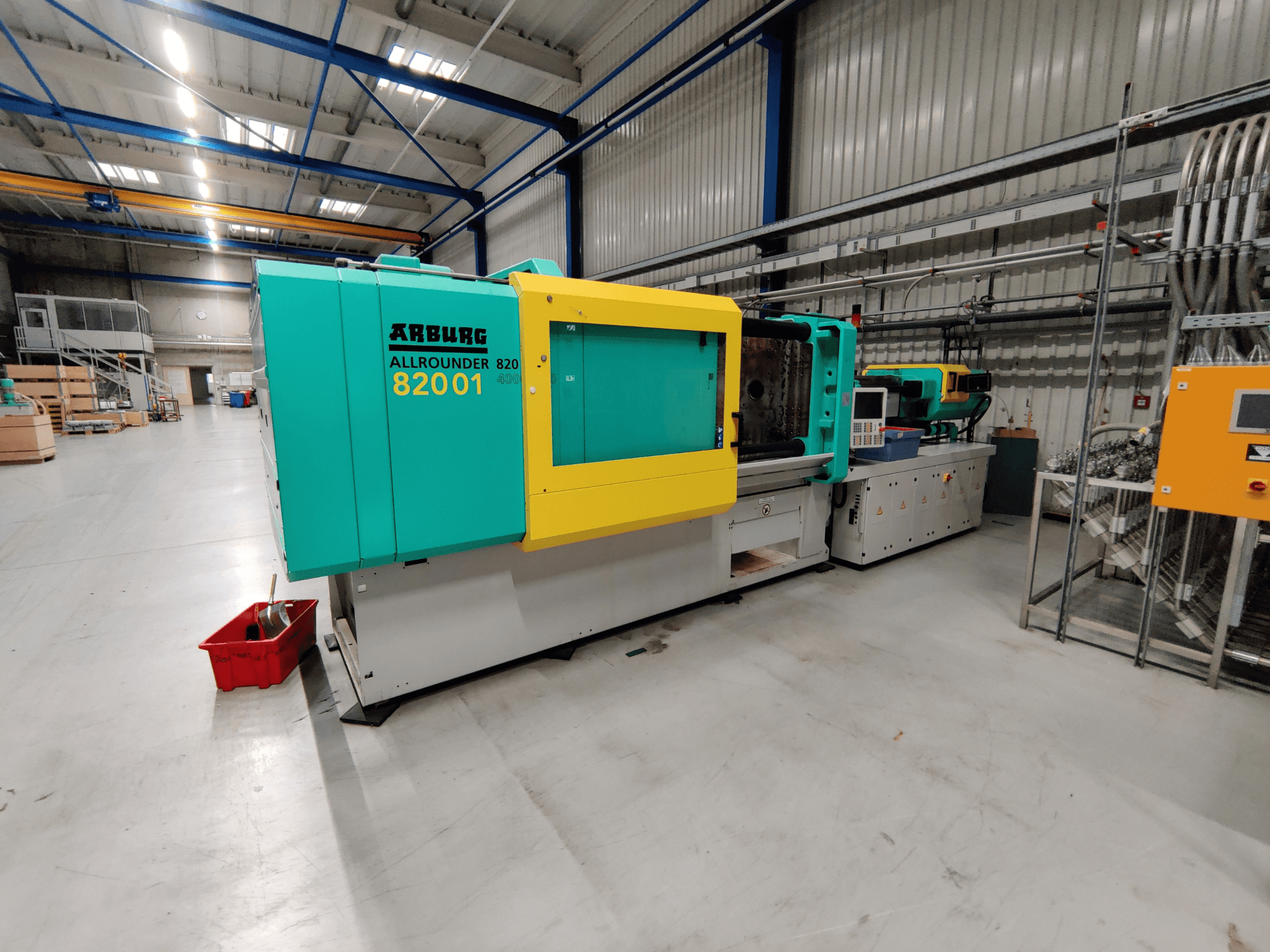 Egy Arburg 820 S 4000-2100 hidraulikus fröccsöntőgép előlapja, élénkzöld és sárga panelekkel.