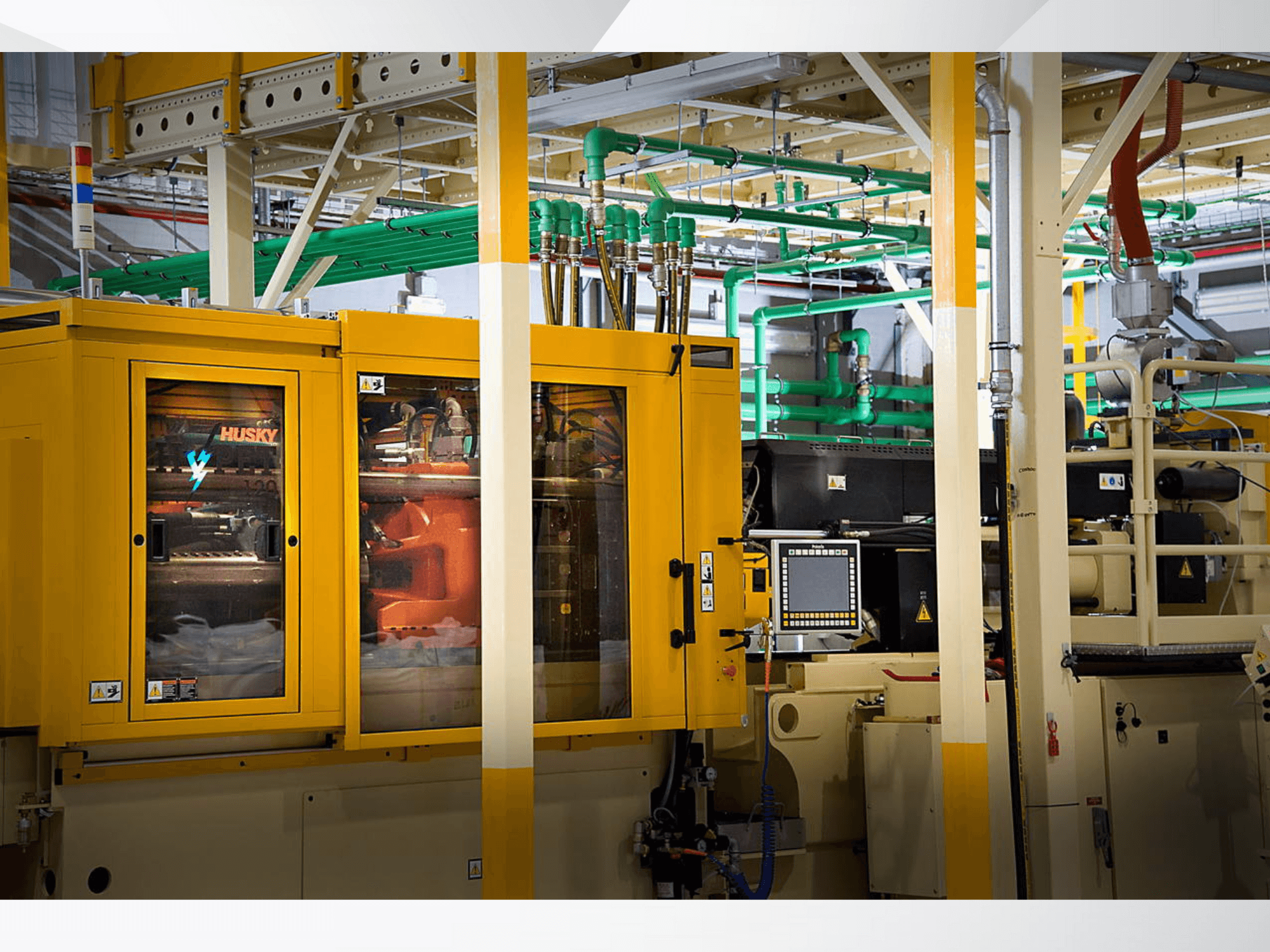 Husky ipari gép sárga színben, elölnézetben a vezérlőpanel és a belső mechanizmusok gyári háttér előtt.
