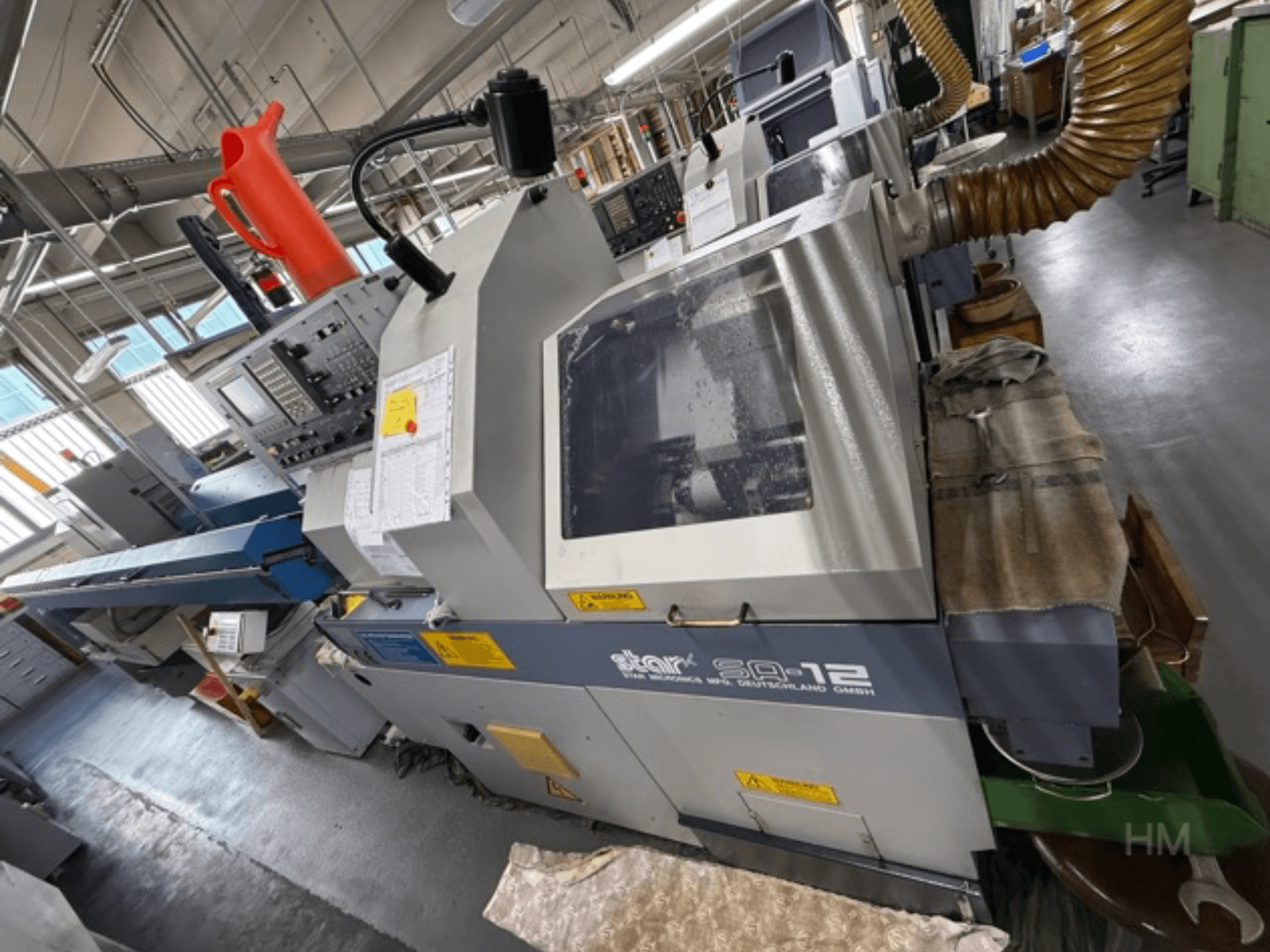 Star SQ-12 megmunkálóközpont, oldalnézet a vezérlőpanel, a hűtőfolyadék-tartály és a porelszívó tömlő látható.