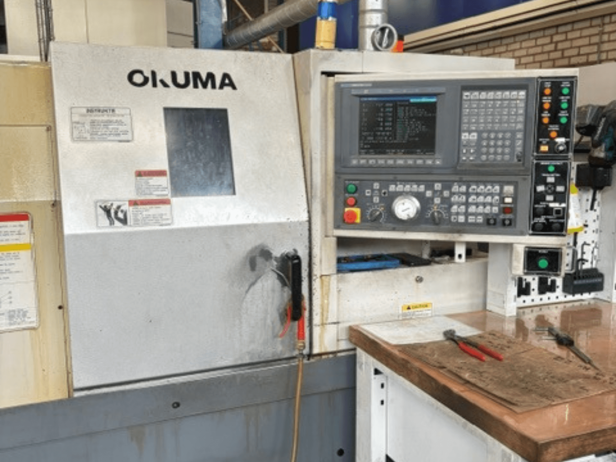 Az Okuma ES-L10II vízszintes eszterga elölnézete, amelyen látható a vezérlőpanel, a kijelző és a szerszámokkal ellátott munkaterület.