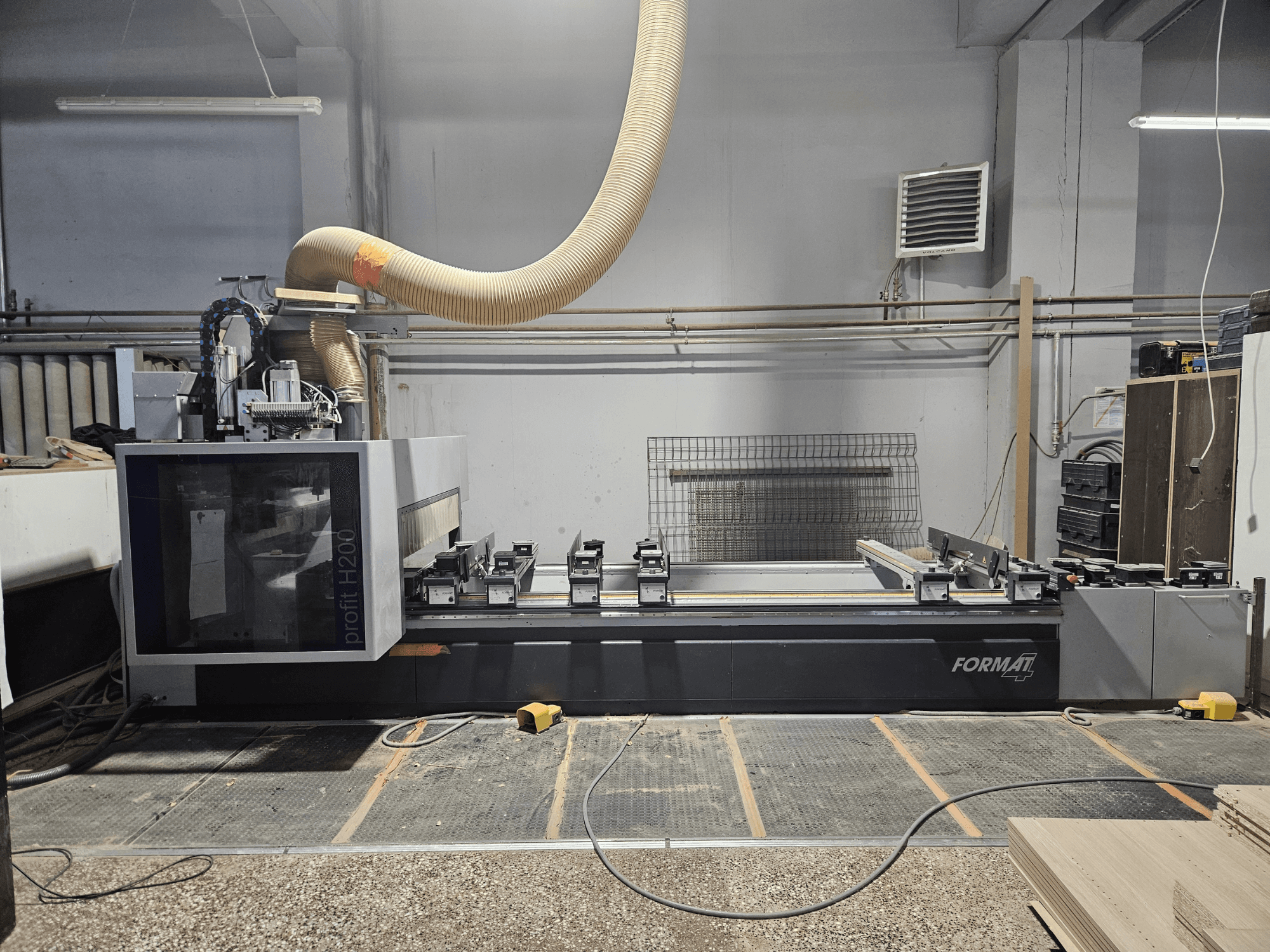 Egy FORMAT profit H200 CNC-gép egy műhelyben, oldalnézetben, a munkafelület és a porelszívó rendszer látható.