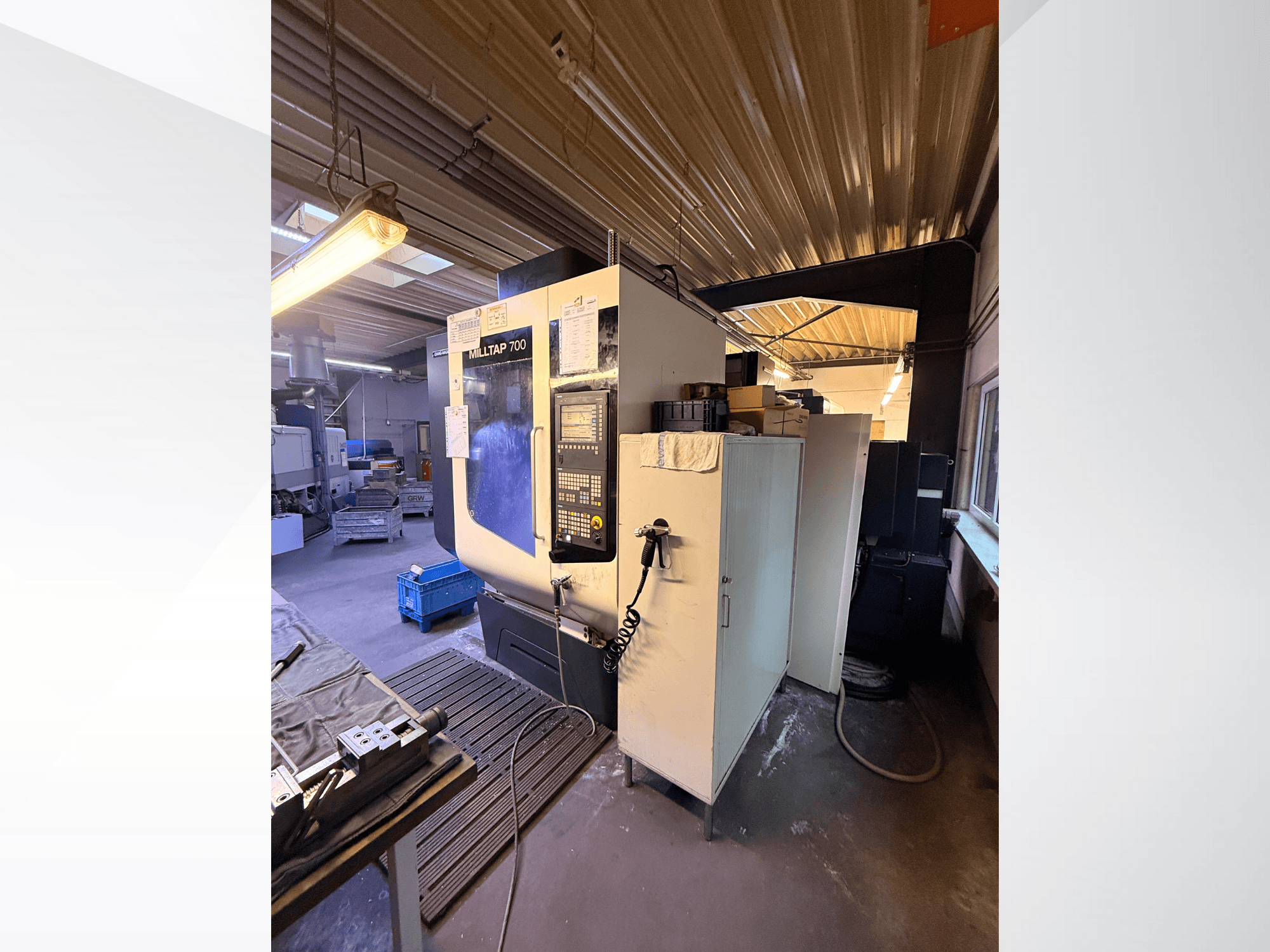 Milltap 700 CNC-gép a műhelyben; elölnézetben a vezérlőpanel, a szerszámtartók és a tárolóterek, felette világítással.
