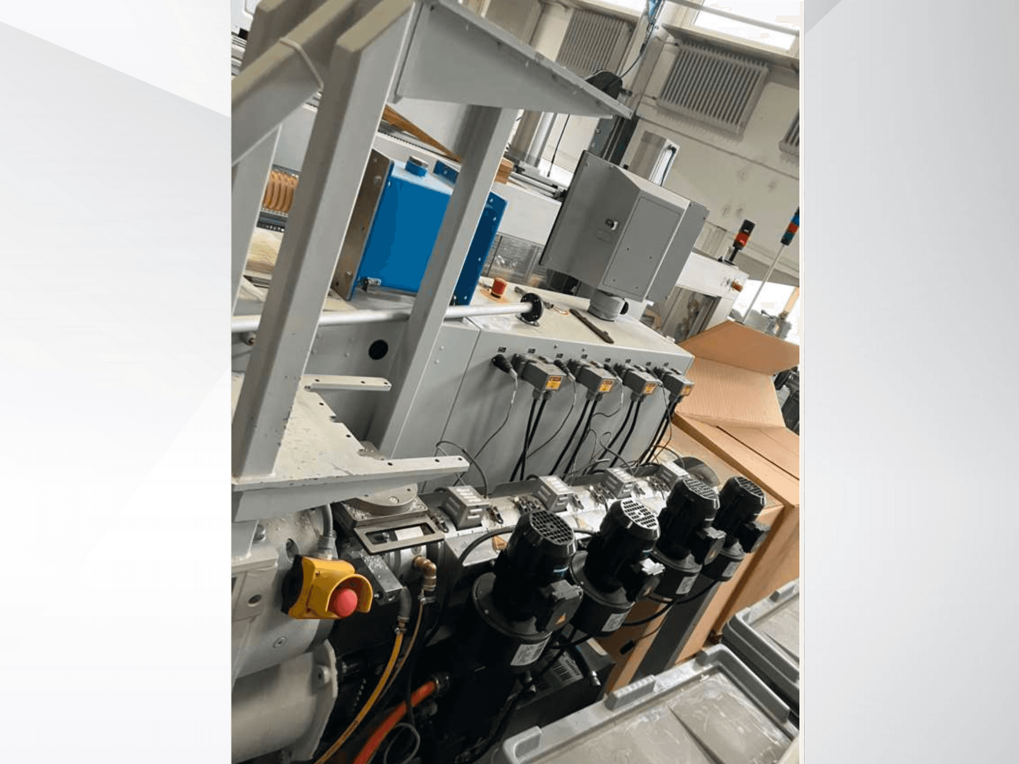 Ipari gépek vezérlőpanelje több motorral, műszerekkel és monitorral; oldalnézet egy gyárban.