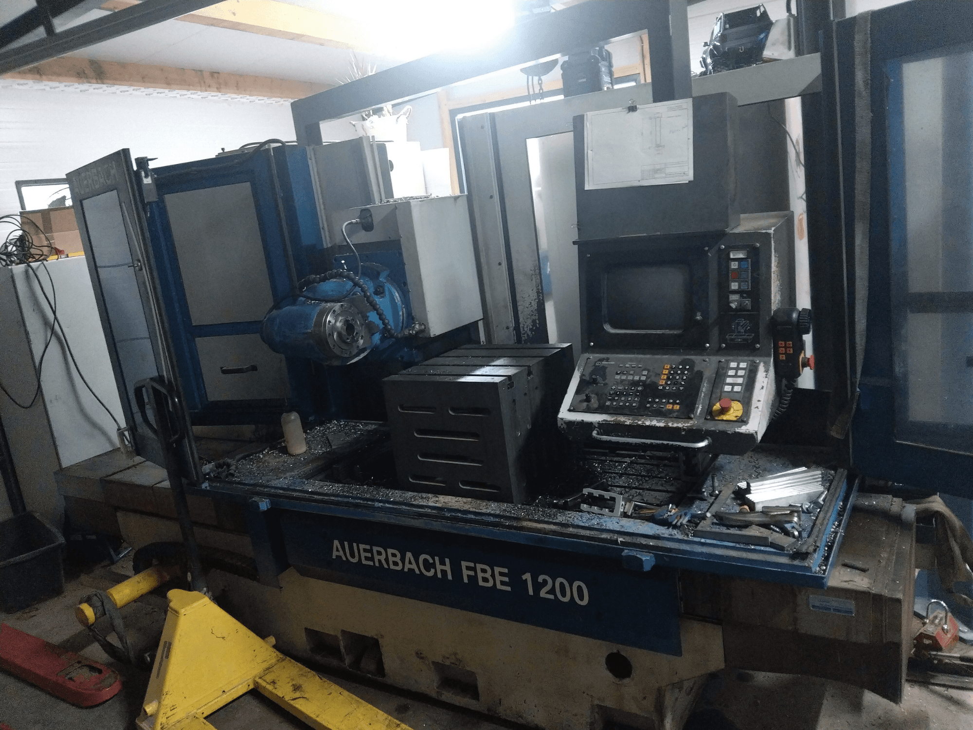 Auerbach FBE 1200 fémfúrógép, előlnézet, a vezérlőpanel, a motor és a fémforgácsok a munkafelületen.