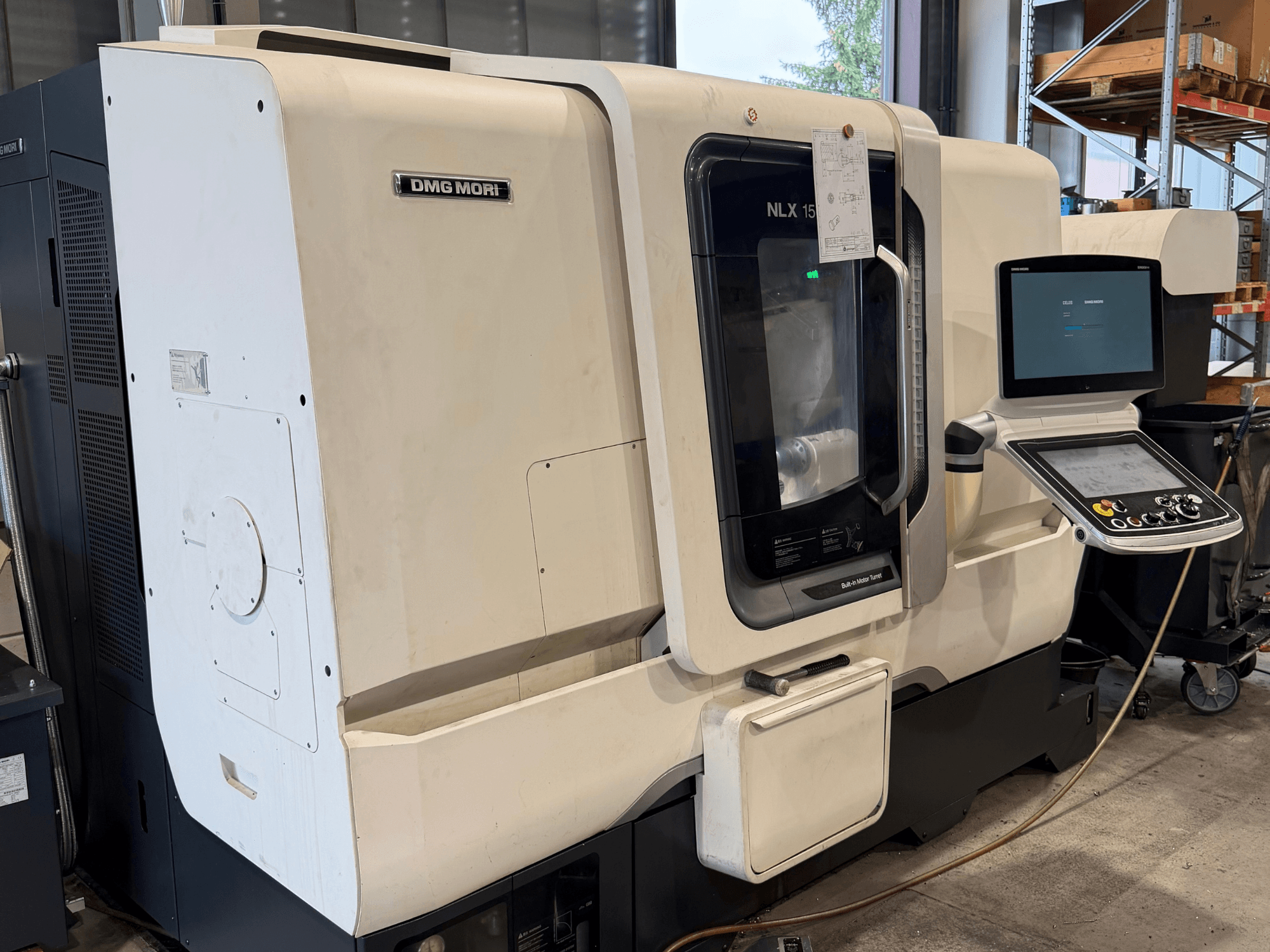 A DMG MORI NLX1500MC/500 vízszintes eszterga elölnézete, amelyen az átlátszó burkolaton keresztül látható a vezérlőpanel és az orsóterület.
