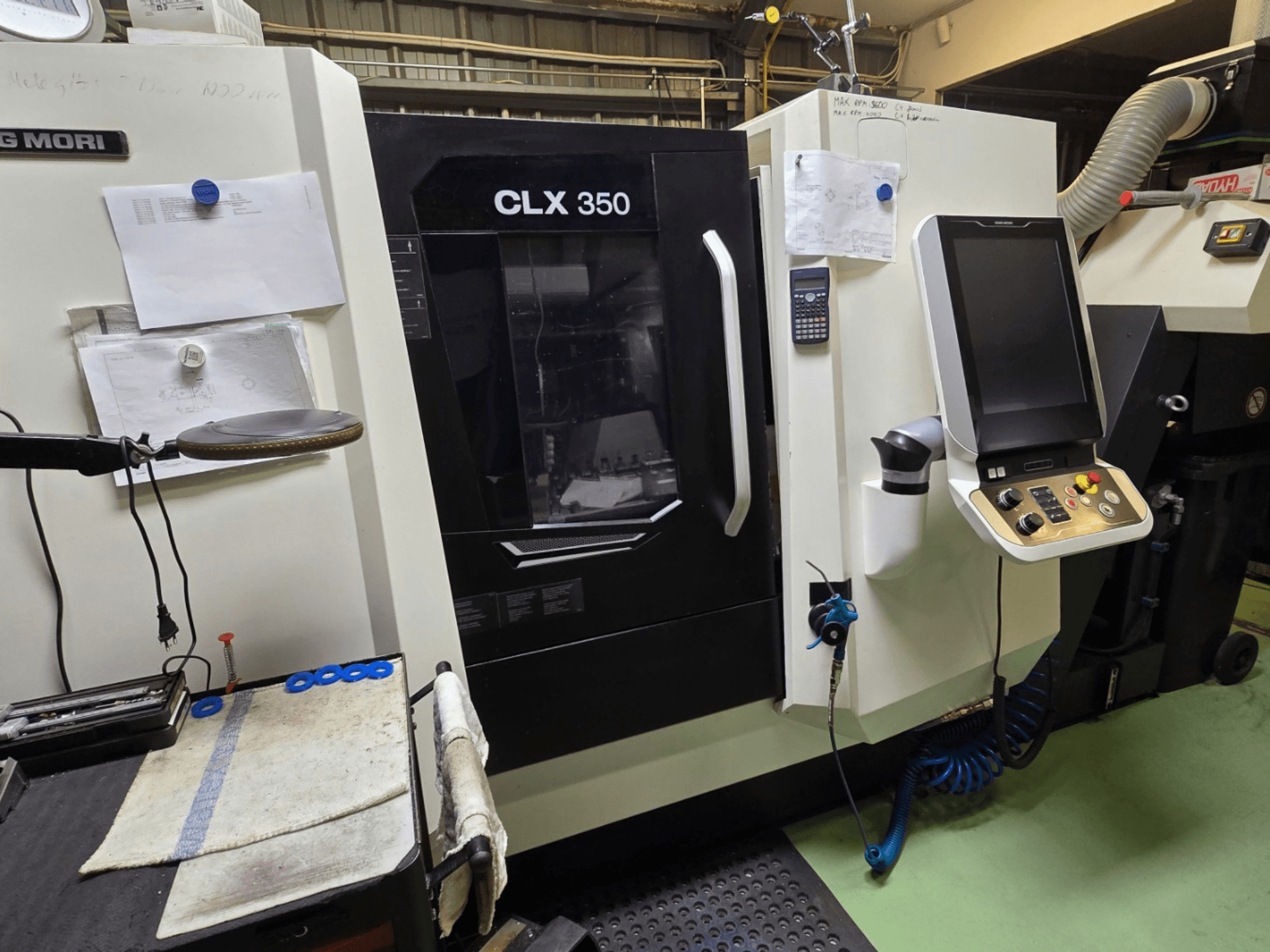 DMG MORI CLX 350 CNC eszterga egy műhelyben; elölnézetben a vezérlőpanel, a szerszámok és a munkaterület látható.