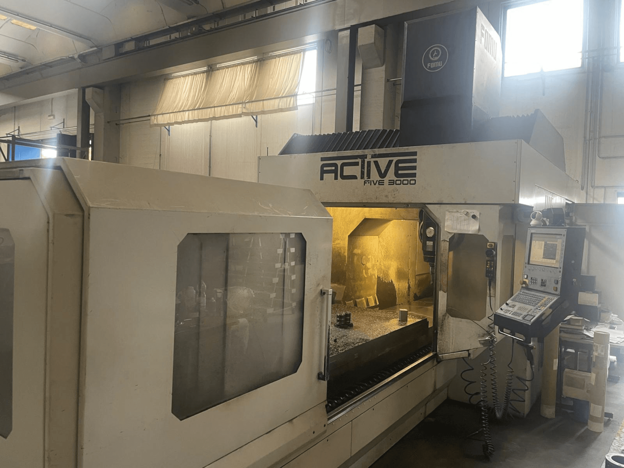 Az ACTIVE Five 3000 CNC-gép elülső nézete, a vezérlőpanel és a munkaterület látható, benne a részben megmunkált alkatrésszel.