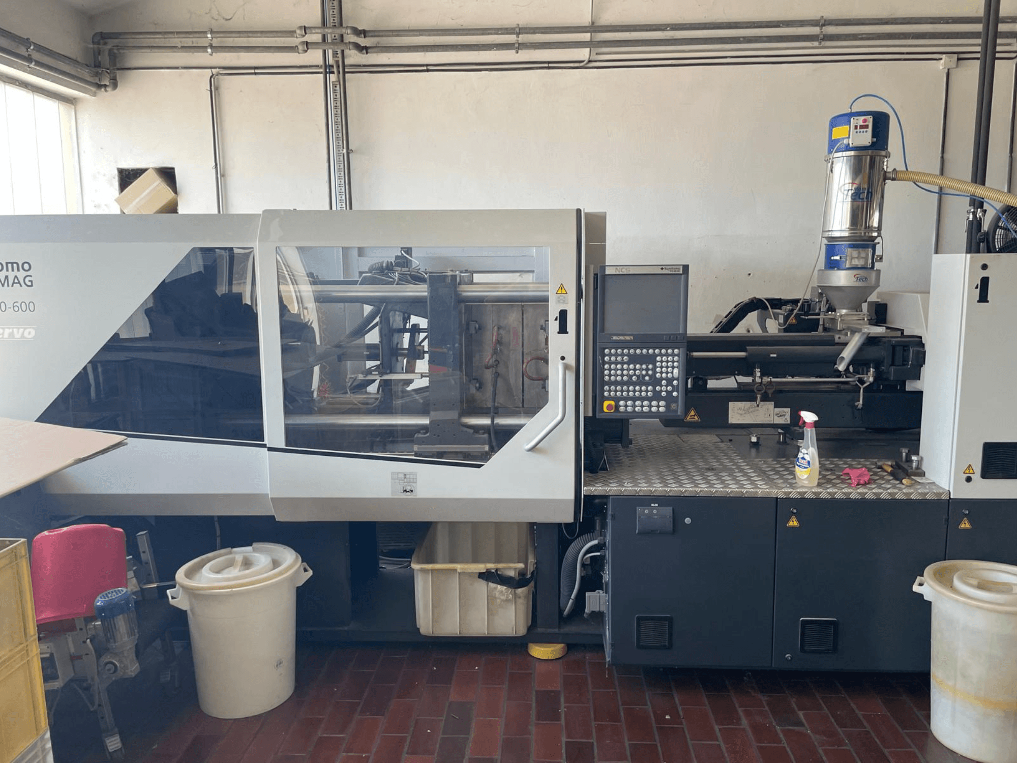 A SUMITOMO SHI DEMAG Systec 160/520-600 hidraulikus fröccsöntőgép előlnézetből, vezérlőpanellel és adagolóegységgel.