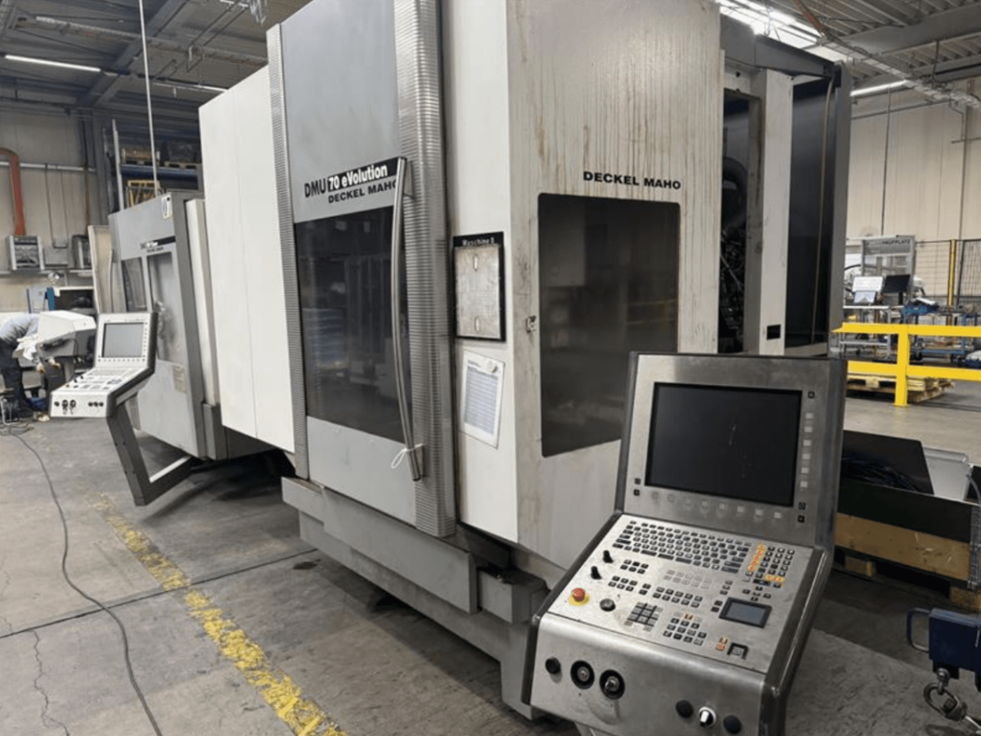 Egy Deckel Maho DMU 70 eVOLUTION CNC-gép előlnézetből, vezérlőpanellel, egy gyártóüzemben.