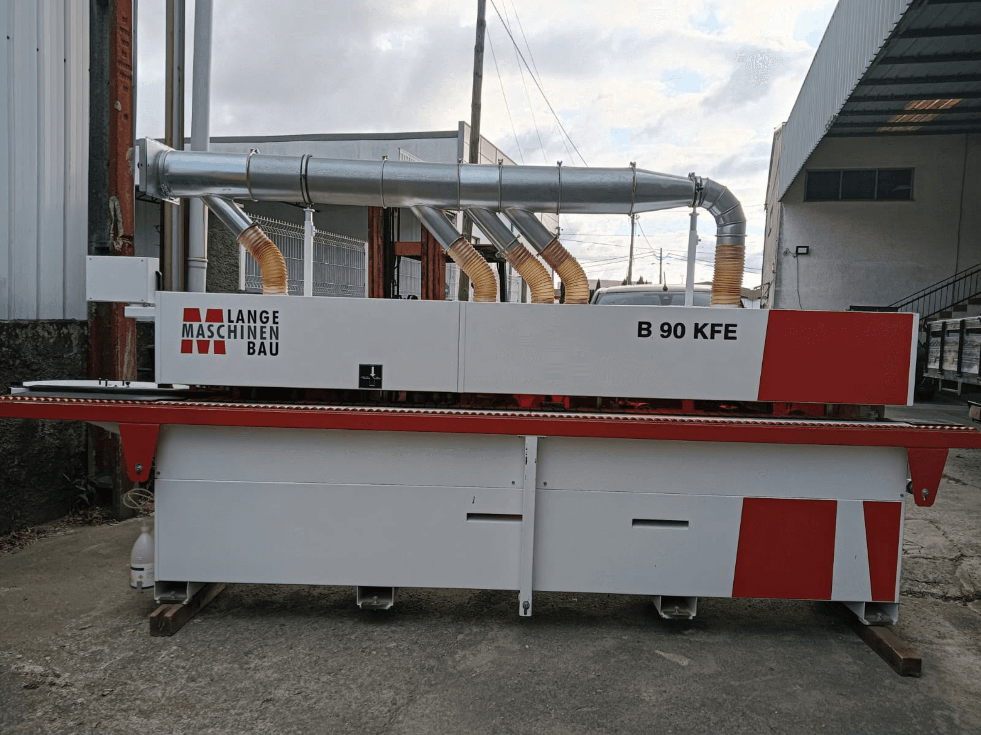 A LANGE Maschinenbau B 90 KFE élragasztó gép oldalnézetben, kettős kipufogócsövekkel és piros díszítésekkel, ipari munkakörnyezetben.