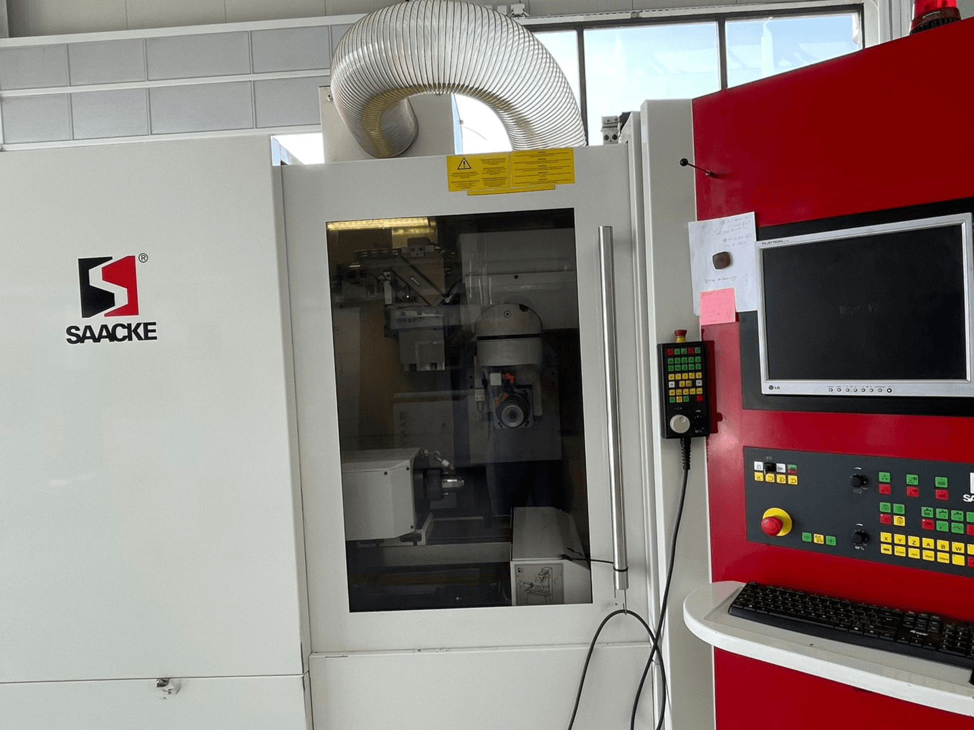 SAACKE gép fehér és piros színben, elölnézetben, vezérlőpanel, monitor és az üvegen keresztül látható belső részek.
