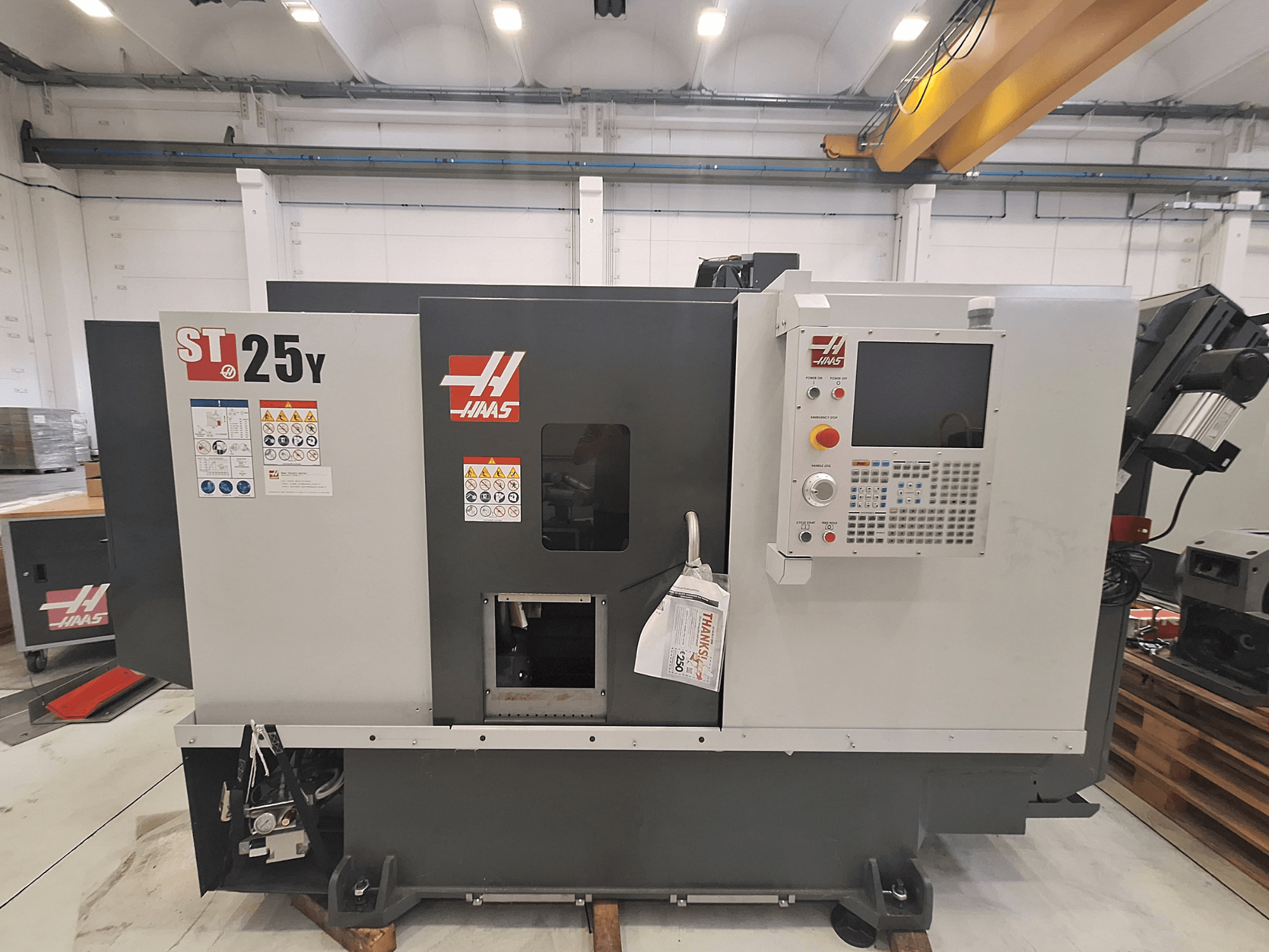Haas ST-25Y vízszintes eszterga, elölnézet, a vezérlőpanellel és a biztonsági címkékkel. Ideális precíziós megmunkáláshoz.