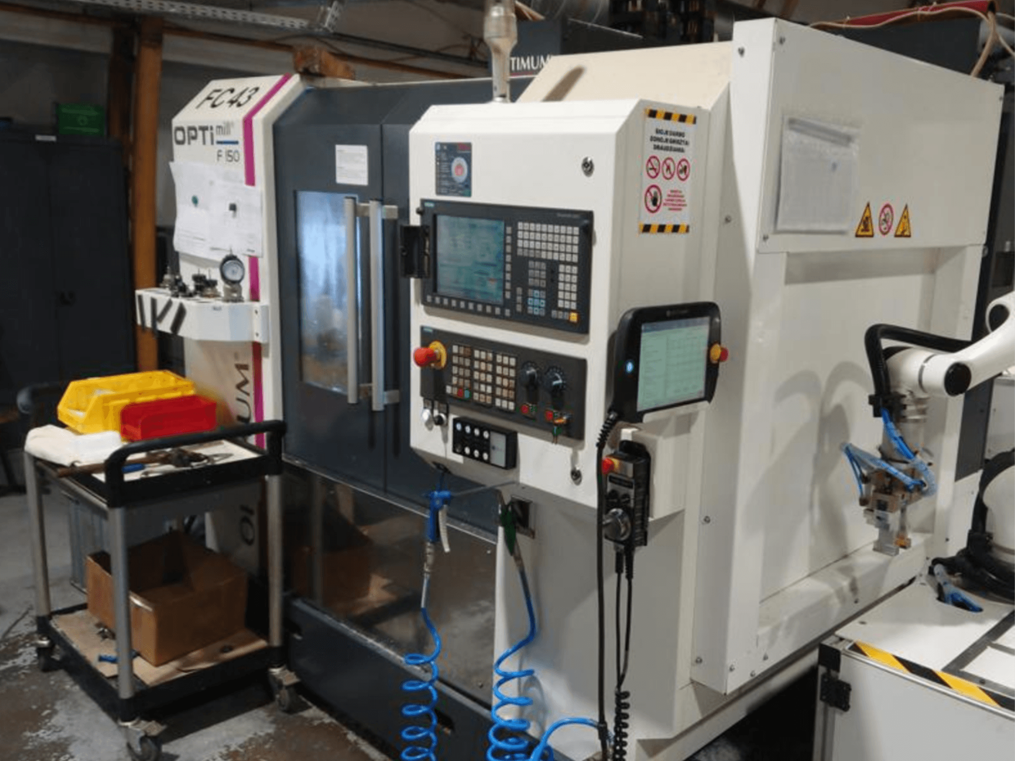 Az OPTIMUM F50 marógép kezelőpanelje tömlőkkel, szerszámokkal és robotkarral műhelyben.