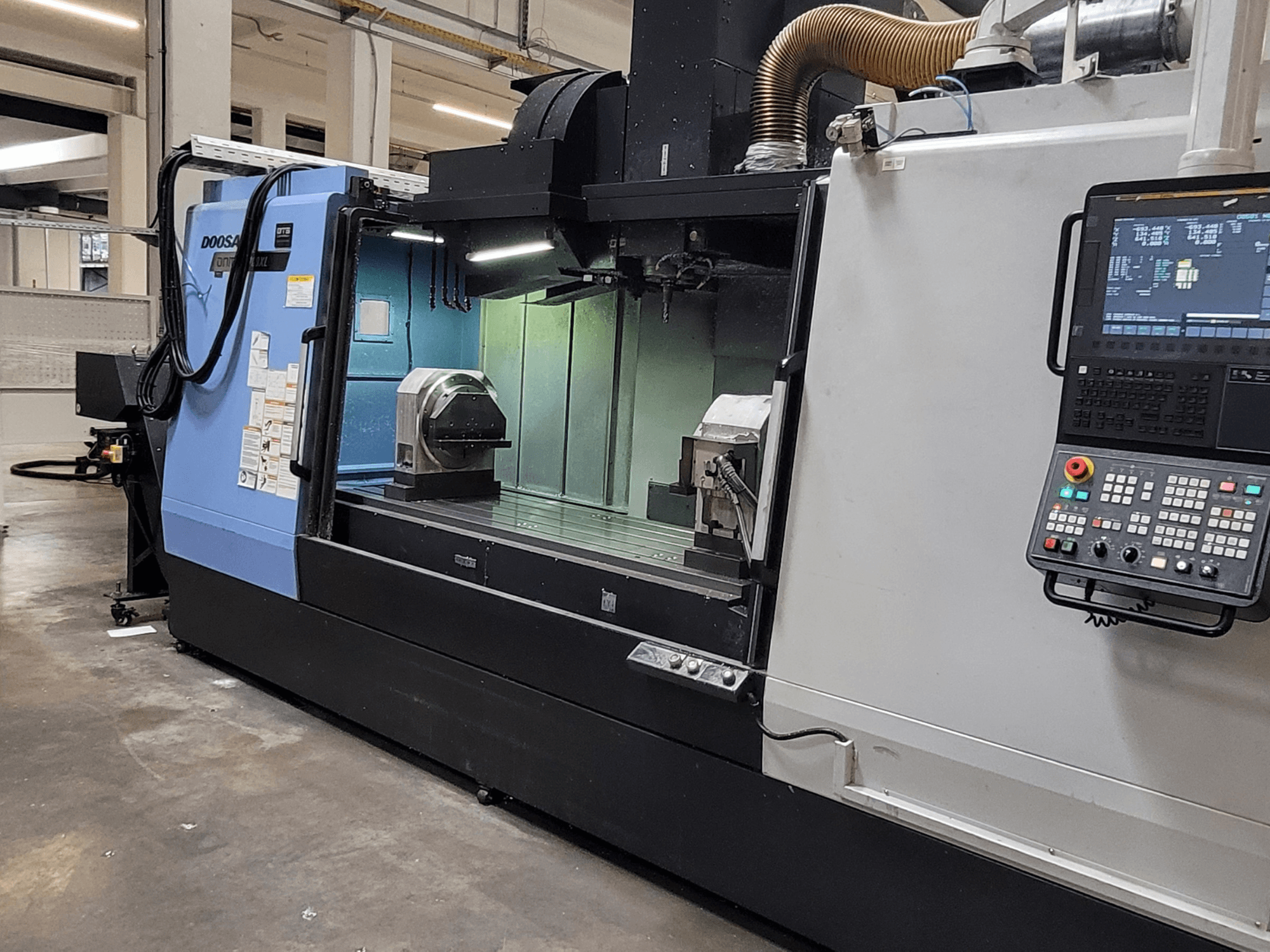 DOOSAN DNM 6700 XL függőleges megmunkáló központ, elölnézet, amelyen látható a vezérlőpanel, a munkapad és a megmunkálási terület.