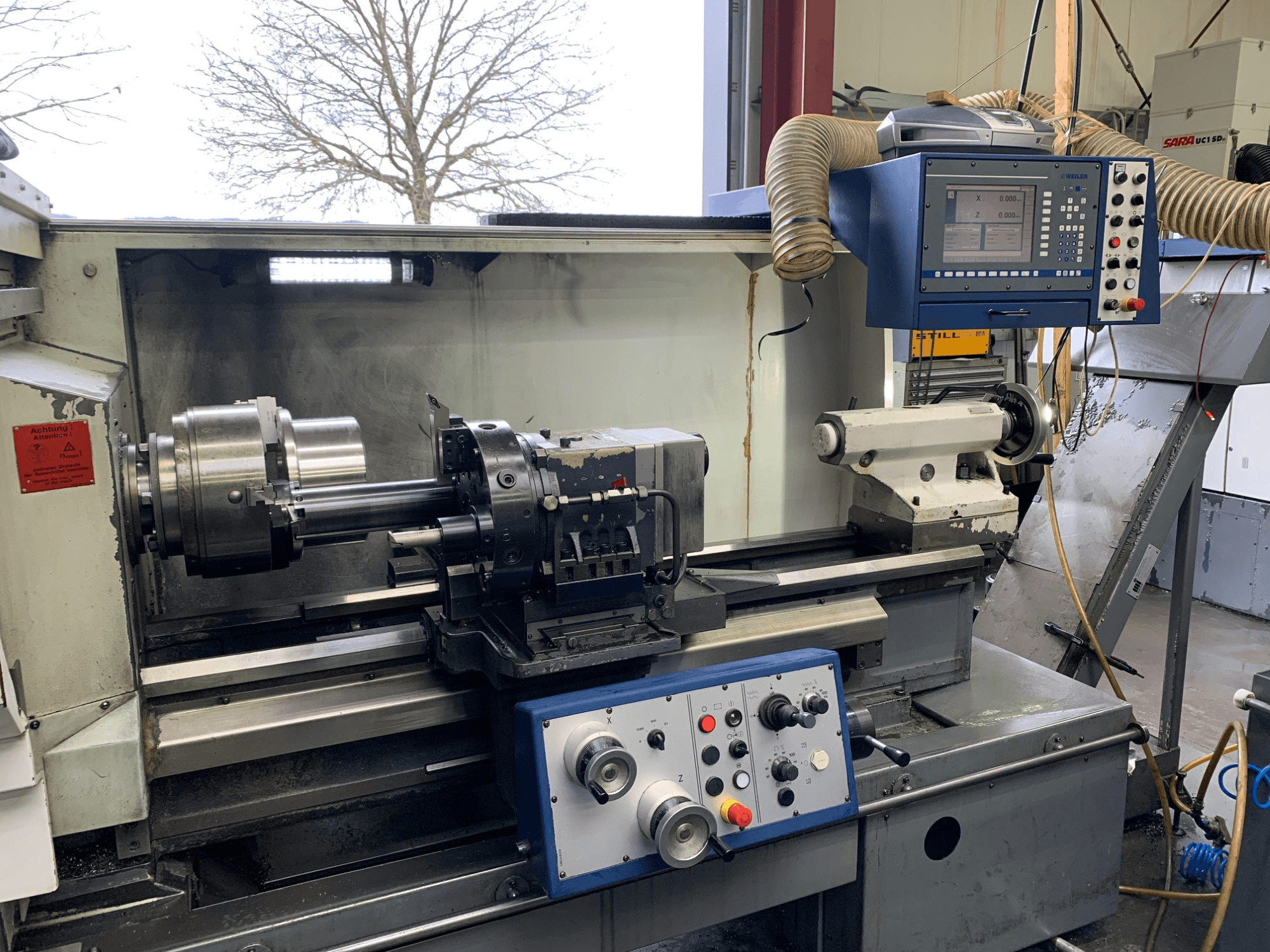 Weiler E55X1000 vízszintes esztergagép egy műhelyben, a kezelőpanel, az eszterga és a szerszámtartó. Előlnézet.