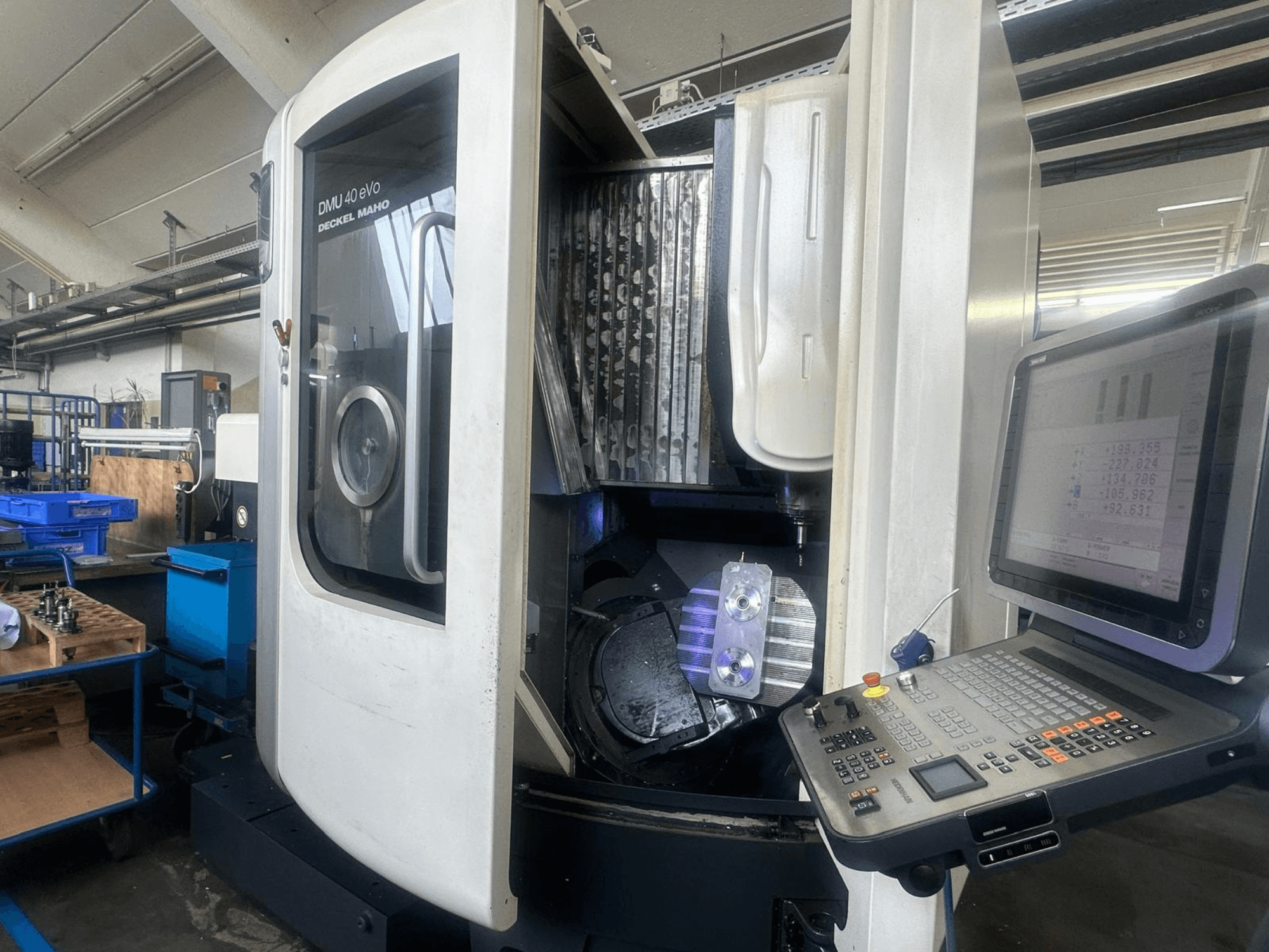 DMU 40 eVo marógép Deckel Maho műhelyben, elölnézetben, a vezérlőpanel és a fémdarab az orsóban.