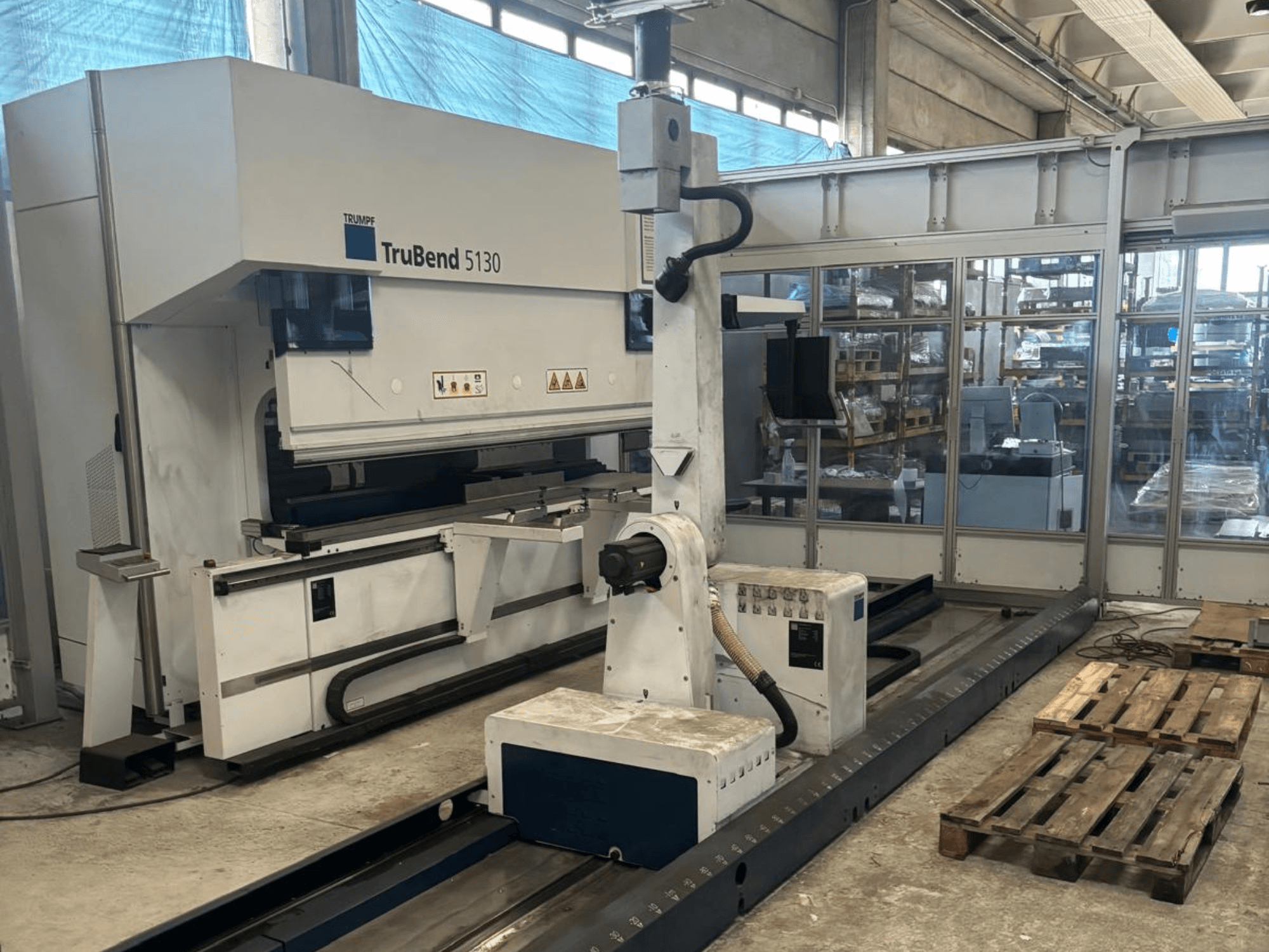 A Trumpf TruBend 5130 hajlítógép, elölnézetben, vezérlőpanellel és raklapokkal, gyári környezetben.