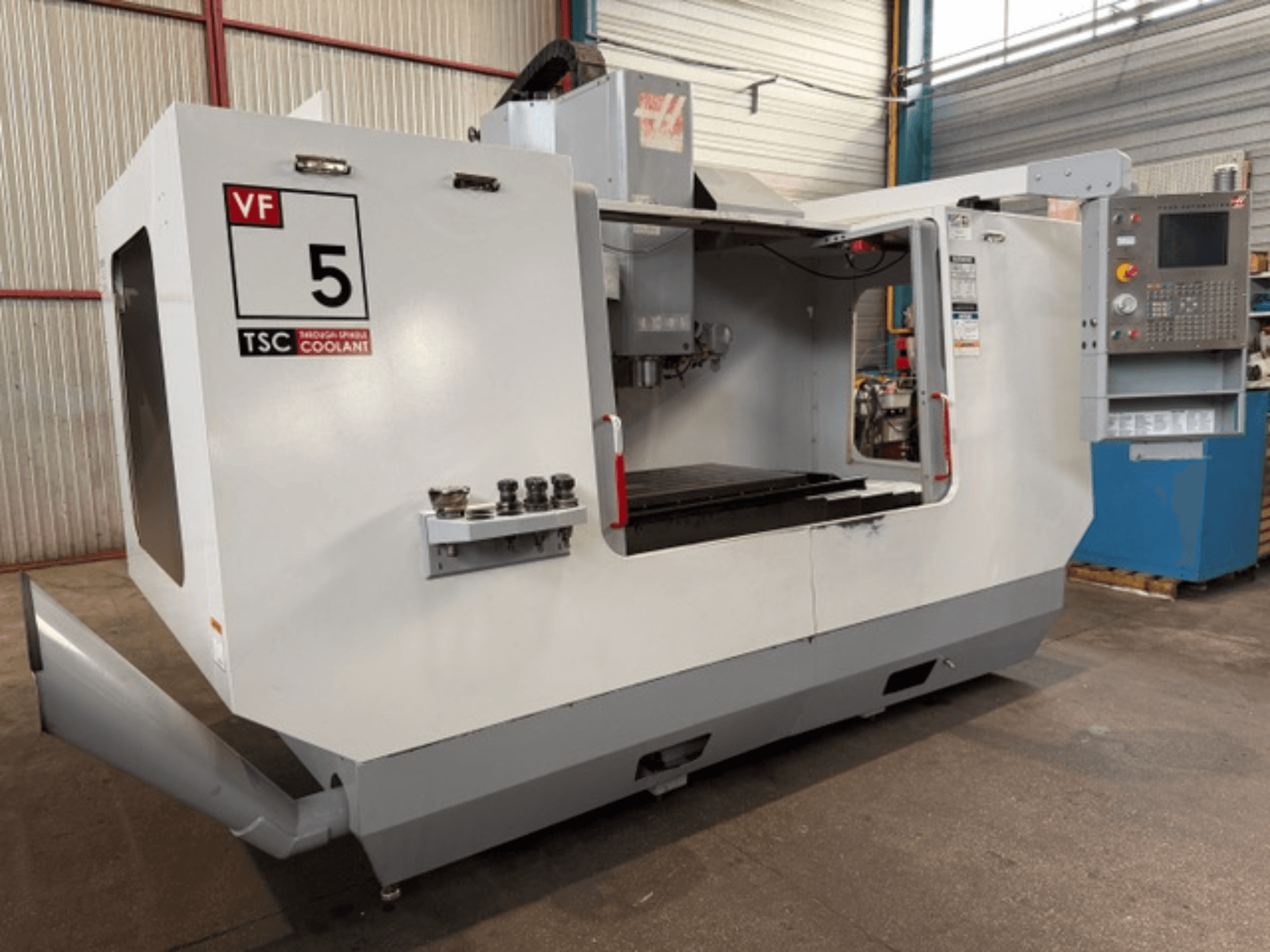 HAAS VF5-HE függőleges megmunkáló központ, elölnézet, a TSC hűtőfolyadék-rendszerrel és a kezelői vezérlőpanellel.
