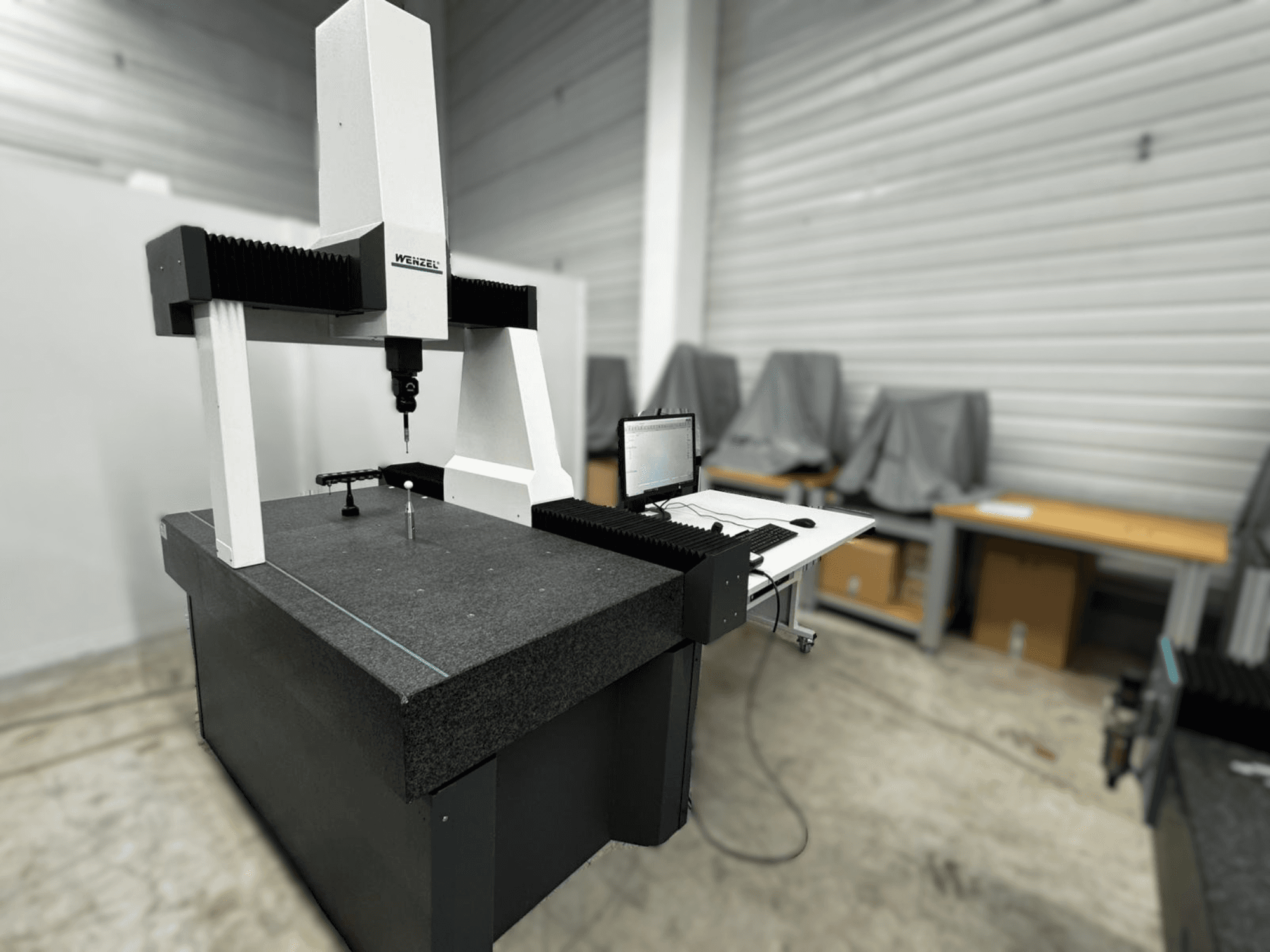 Wenzel LH 54 koordináta-mérőgép oldalnézetben, szürke alapon egy szondával és egy számítógépes interfésszel.