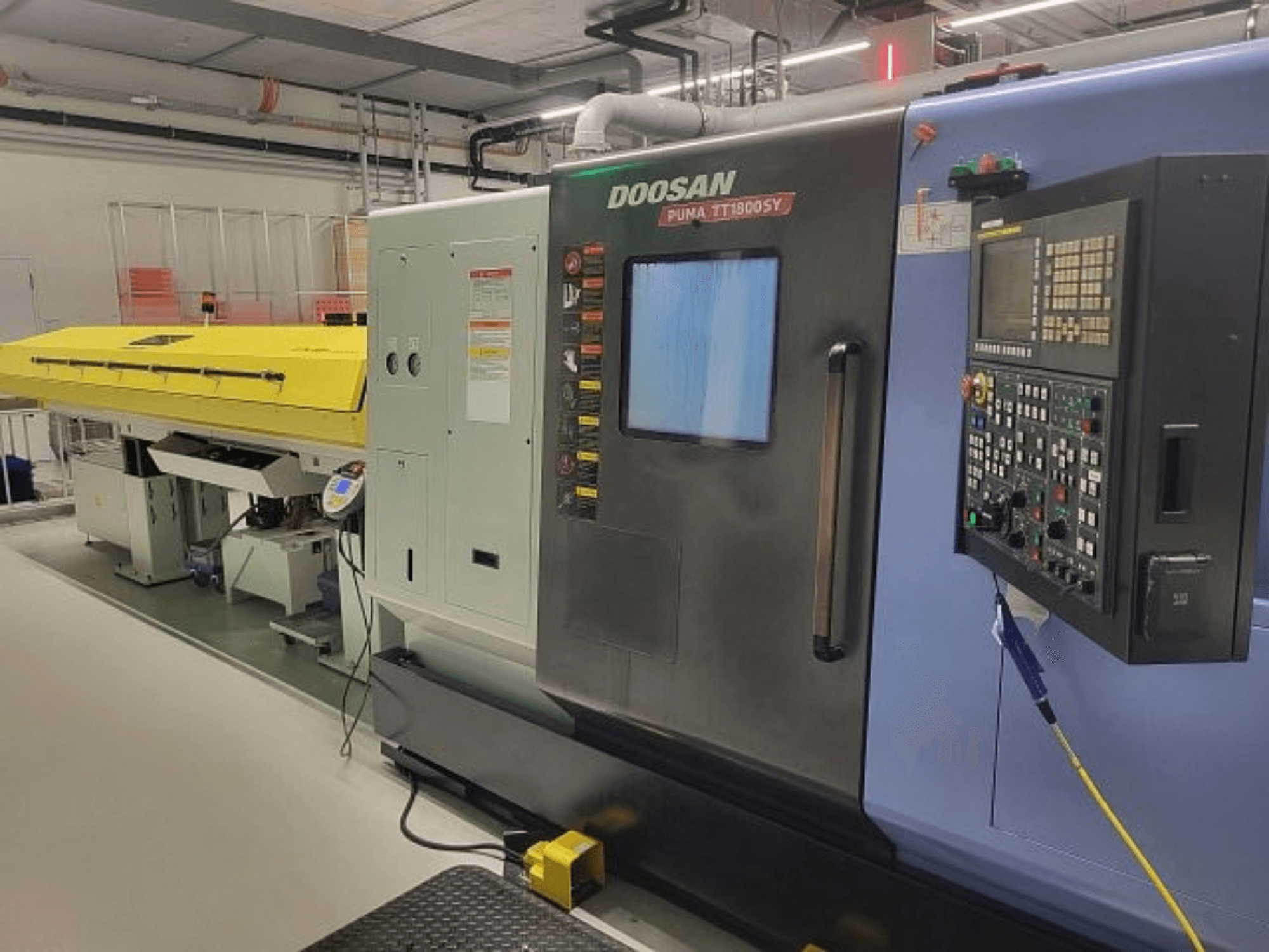 DOOSAN PUMA TT 1800 SY eszterga-marógép, elölnézet a kezelőpanellel és a sárga burkolattal, ipari környezetben.