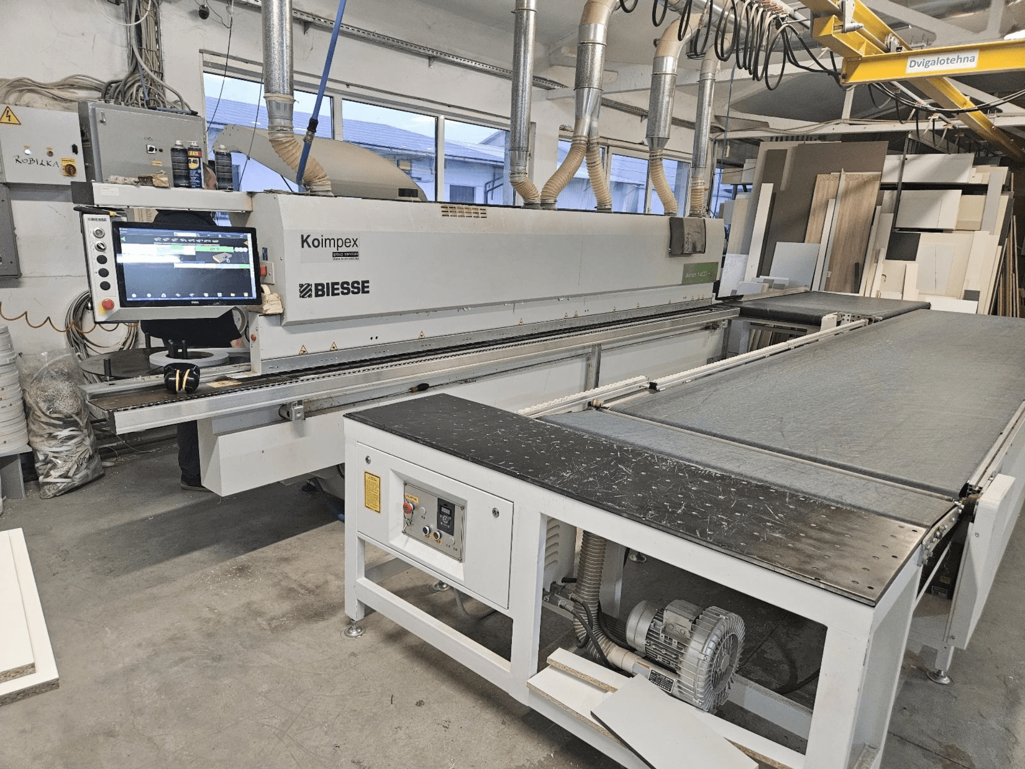 BIESSE Akron 1440 A szegélycsiszoló egy műhelyben, oldalnézetben a vezérlőpanel és a szállítószalag.