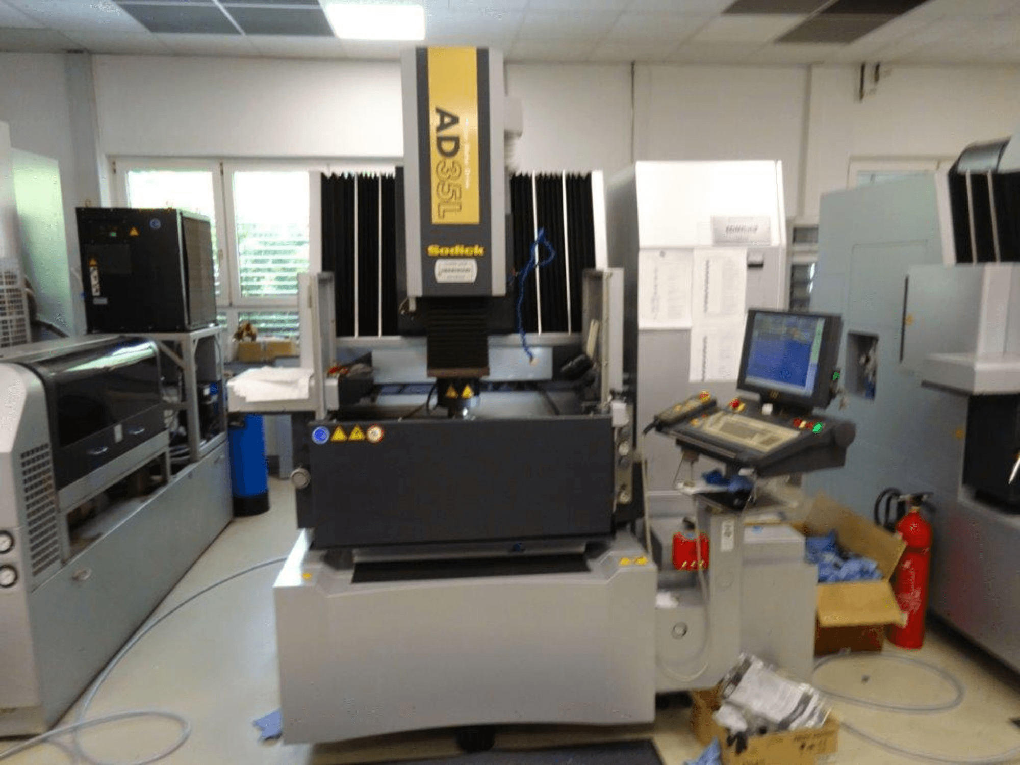 Sodick AD35L CNC-gép elölnézetből, a vezérlőpanel, a hűtőegység és a biztonsági jelzők.