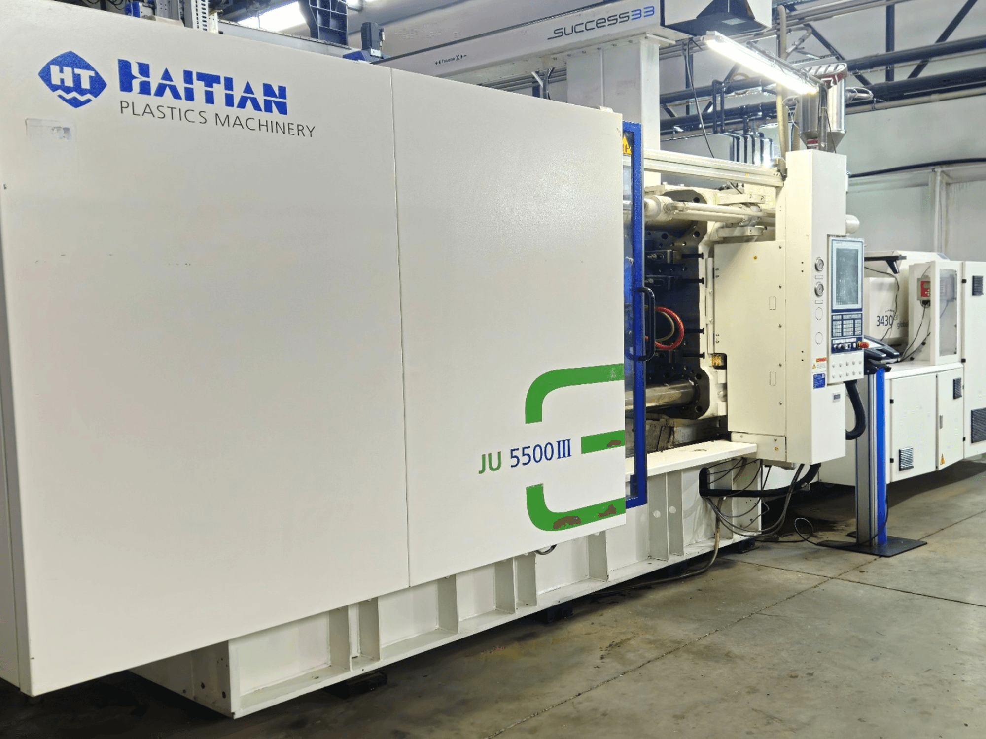 Haiti JU 5500III műanyagipari gép gyári környezetben, elölnézetben a vezérlőpanel és a gyártási terület bemutatása.