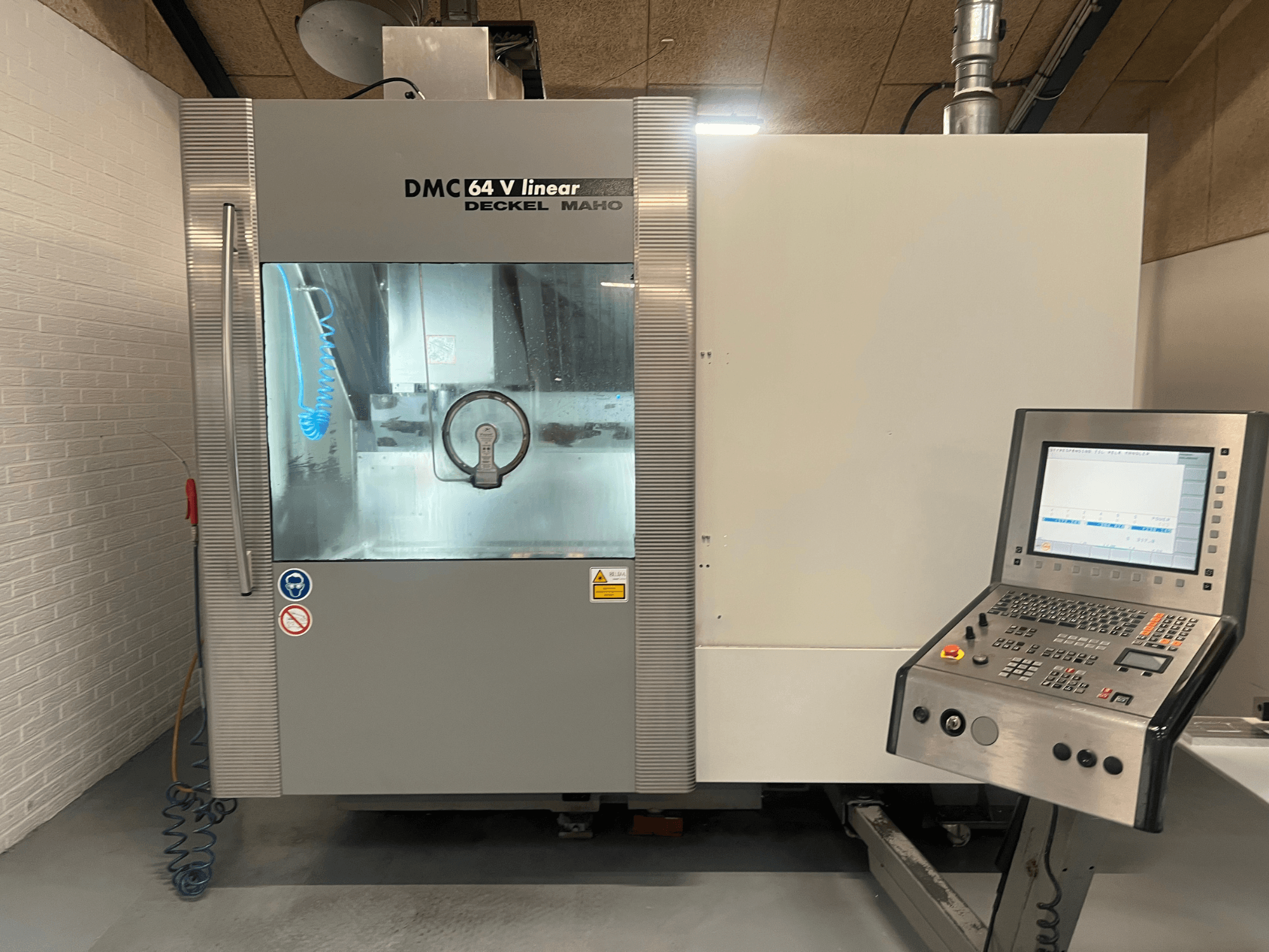 DMC 64 V Linear by Deckel Maho, CNC megmunkálóközpont előlapja, a vezérlőpanel és a hűtőfolyadék fúvóka látható.