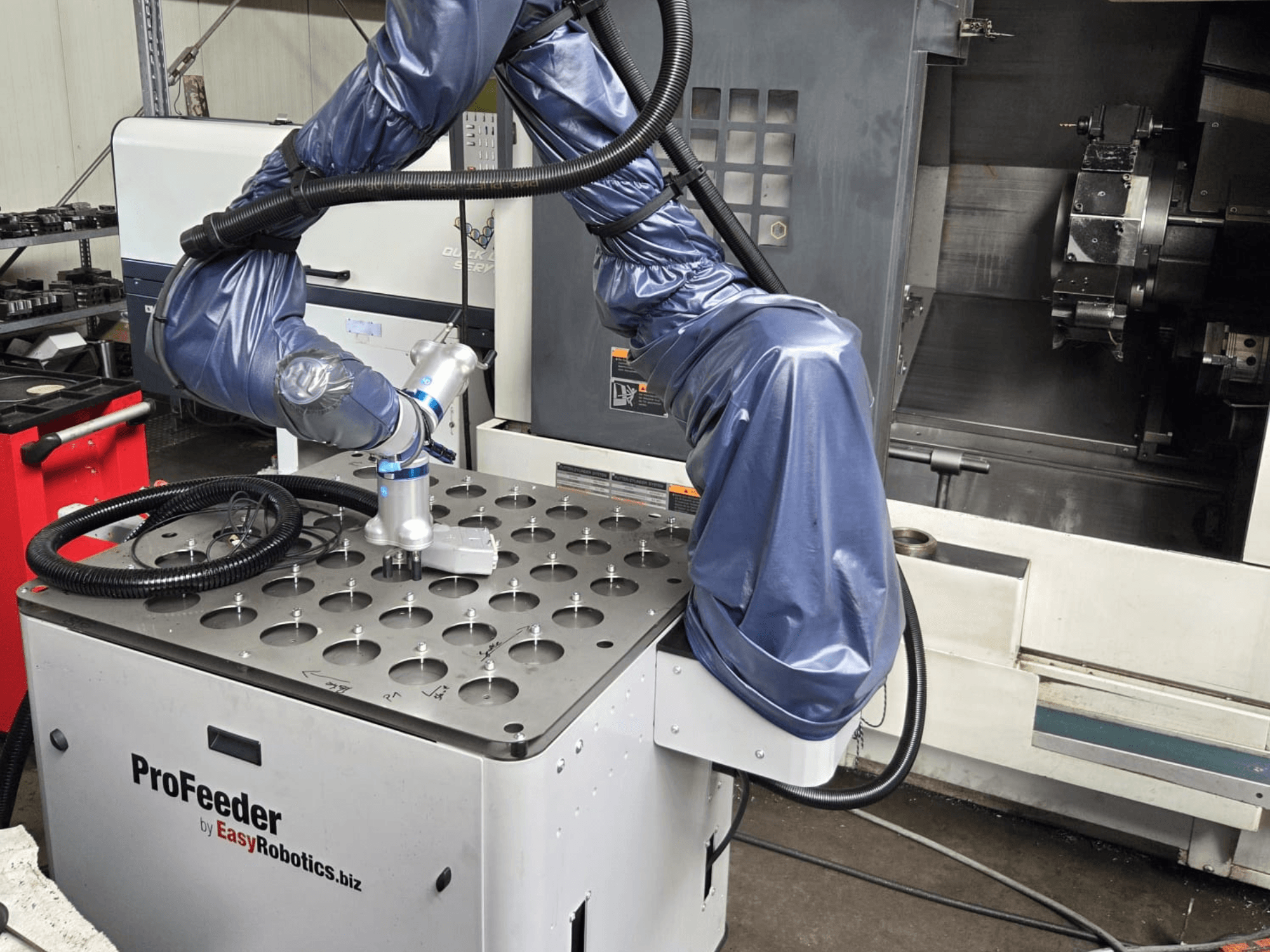 Az EASYROBOTICS ProFeeder együttműködő robot szemből, egy perforált fémasztal fölé helyezett robotkarral.