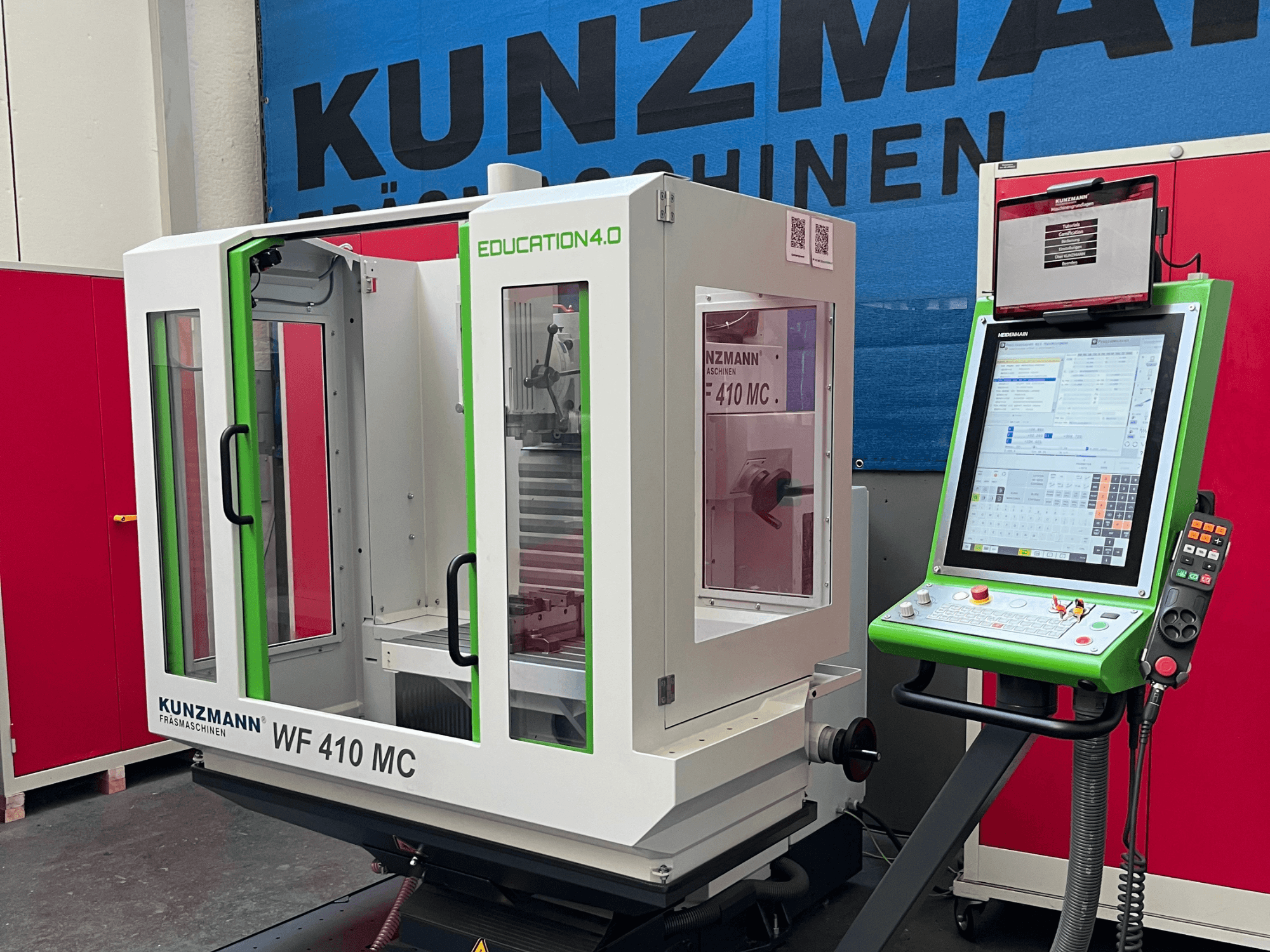 A KUNZMANN WF 410 MC univerzális megmunkáló központ elölnézetben, zöld díszítésekkel, átlátszó ajtókkal és vezérlőpanellel.