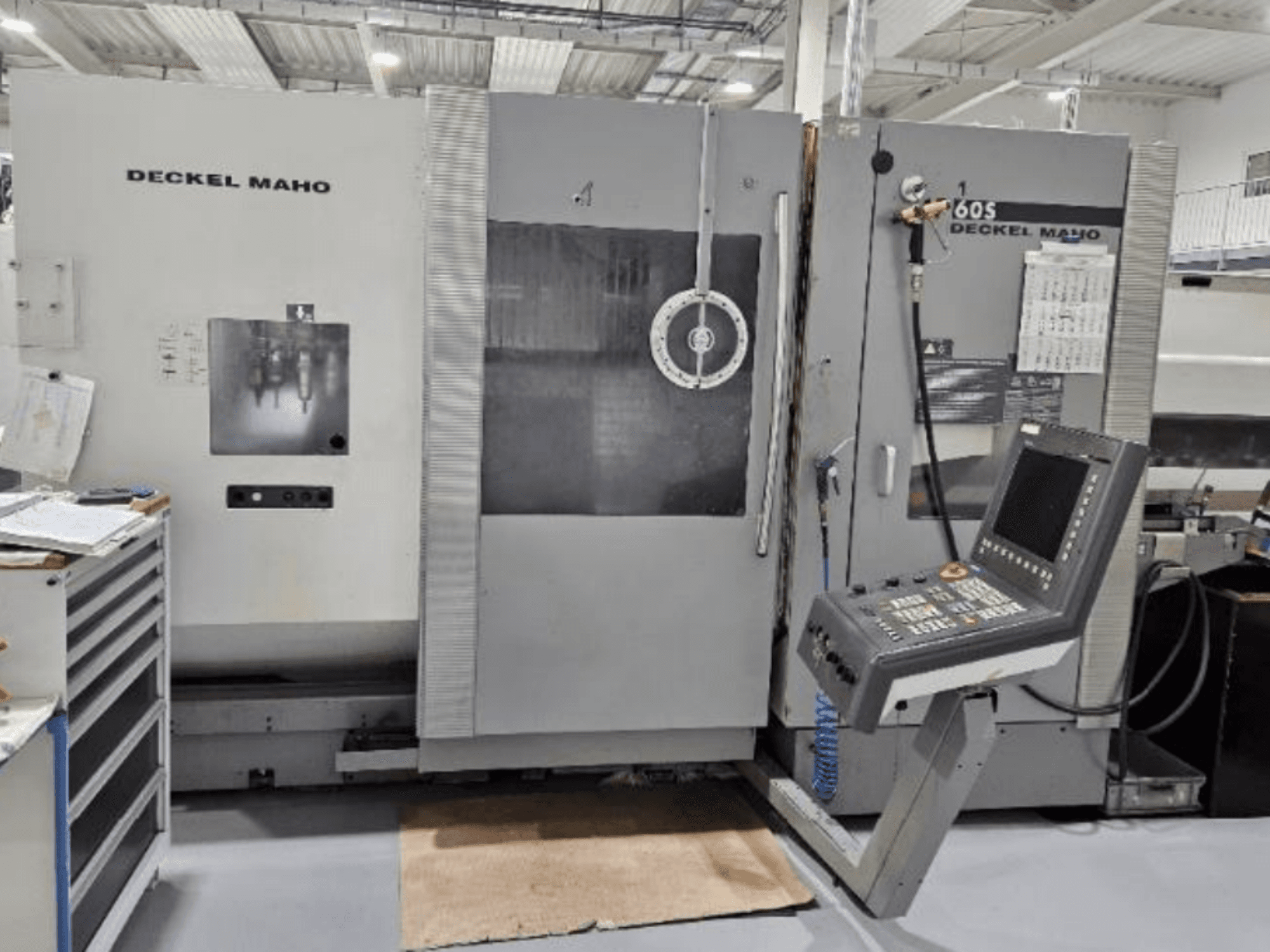 Egy DECKEL MAHO 60S CNC-gép előlapja műhelyben, kezelőpanellel, szerszámok láthatóak.