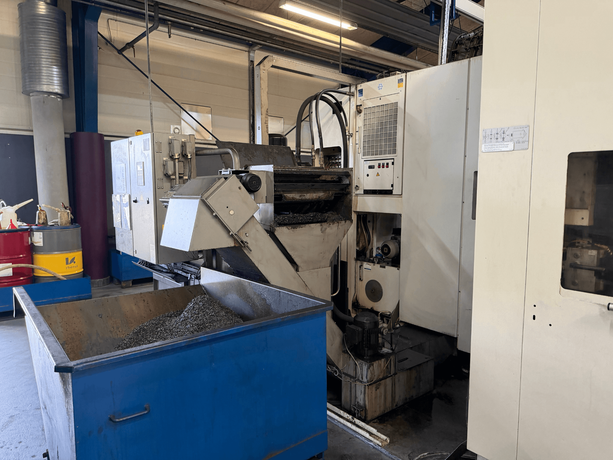 A HELLER MCH 250 vízszintes megmunkálóközpont előlapja, látható a fém hűtőfolyadék újrahasznosító tartály és a kezelőpanel.