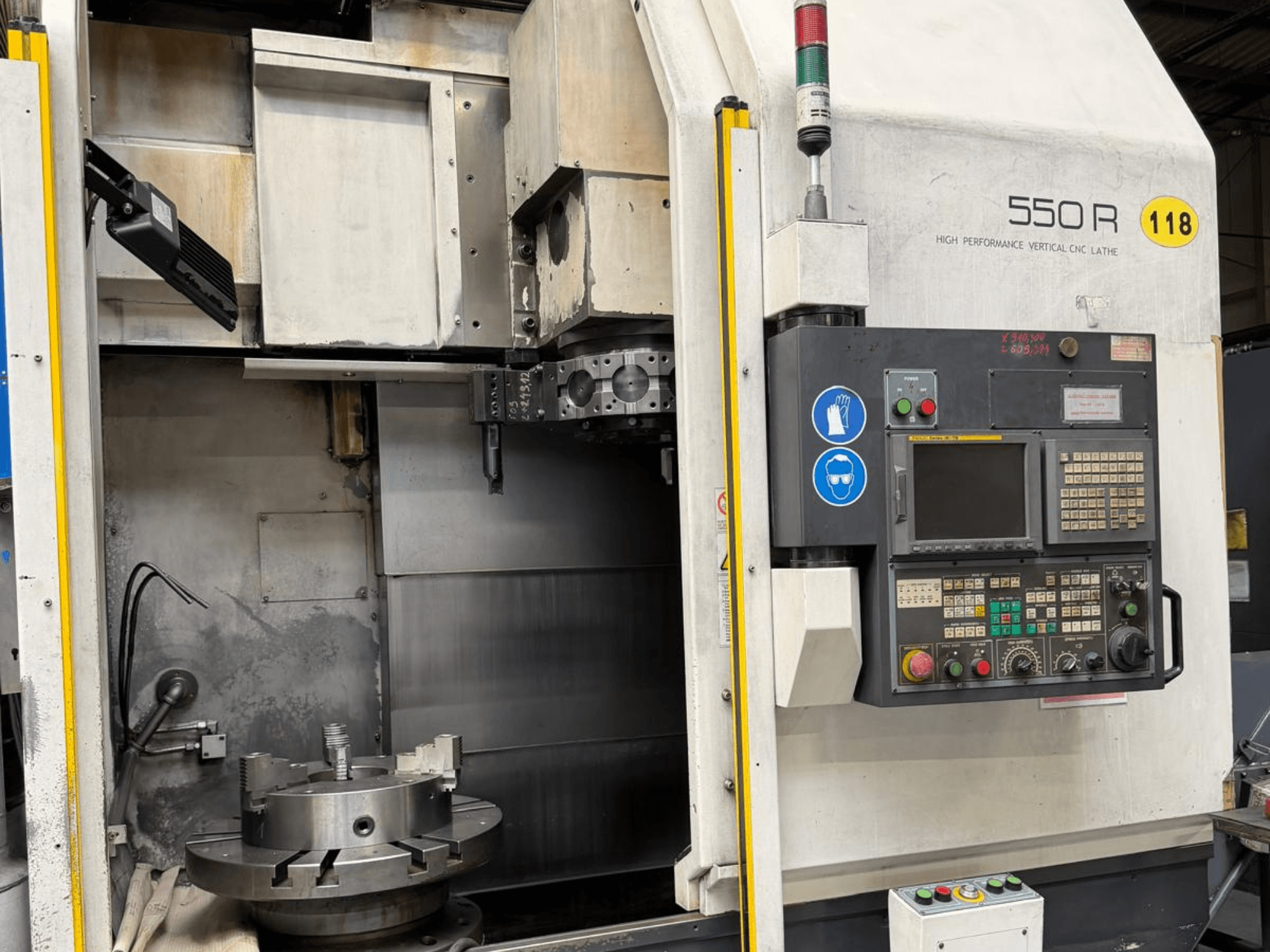 Nagy teljesítményű függőleges CNC eszterga 550 R, előlnézet, a vezérlőpanel, a forgó tokmány és a működtető alkatrészek.