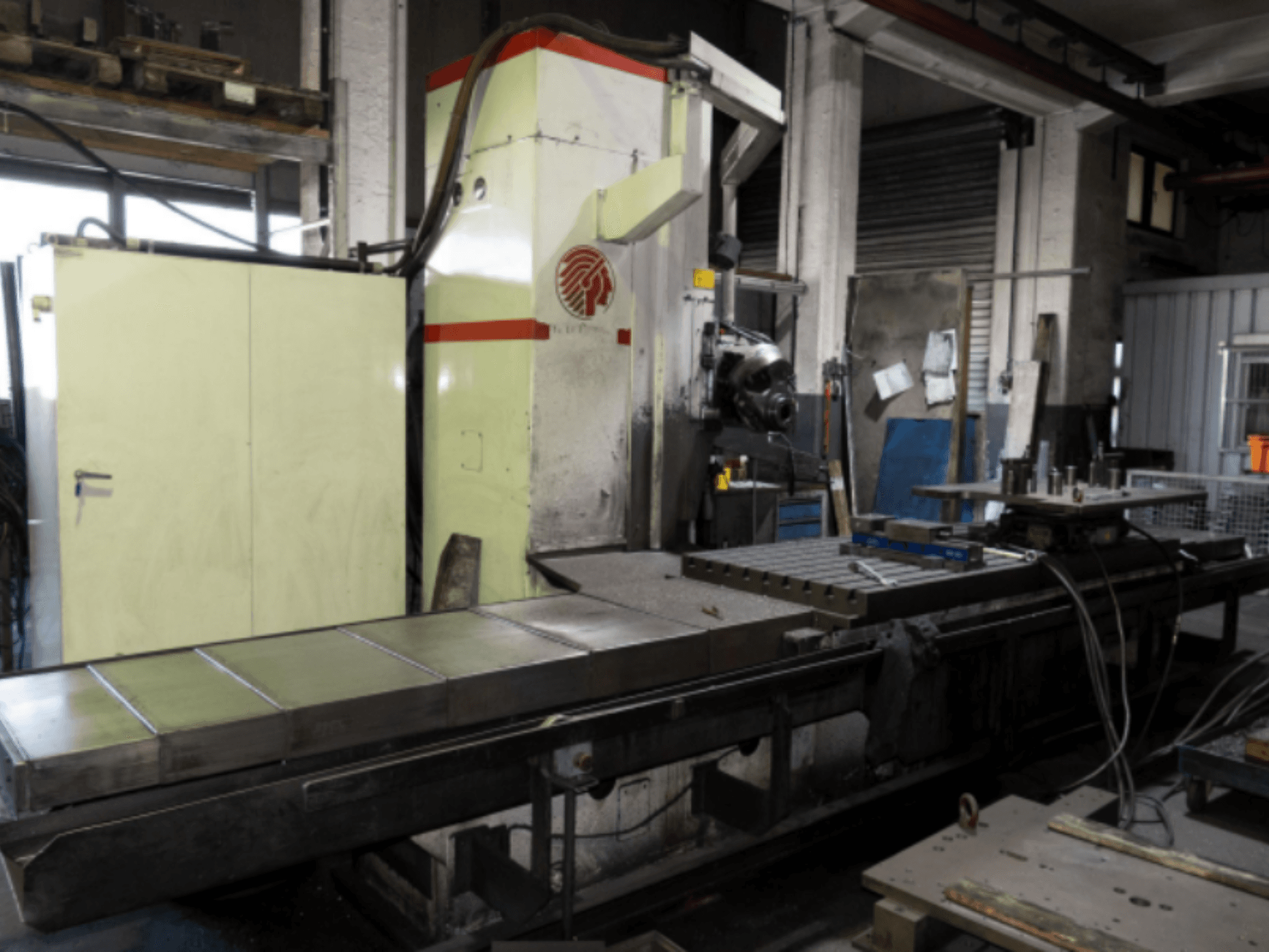 Ipari marógép nagy asztallal, oldalnézetben, a kezelőszervek és a tartozékok bemutatása műhelykörnyezetben.