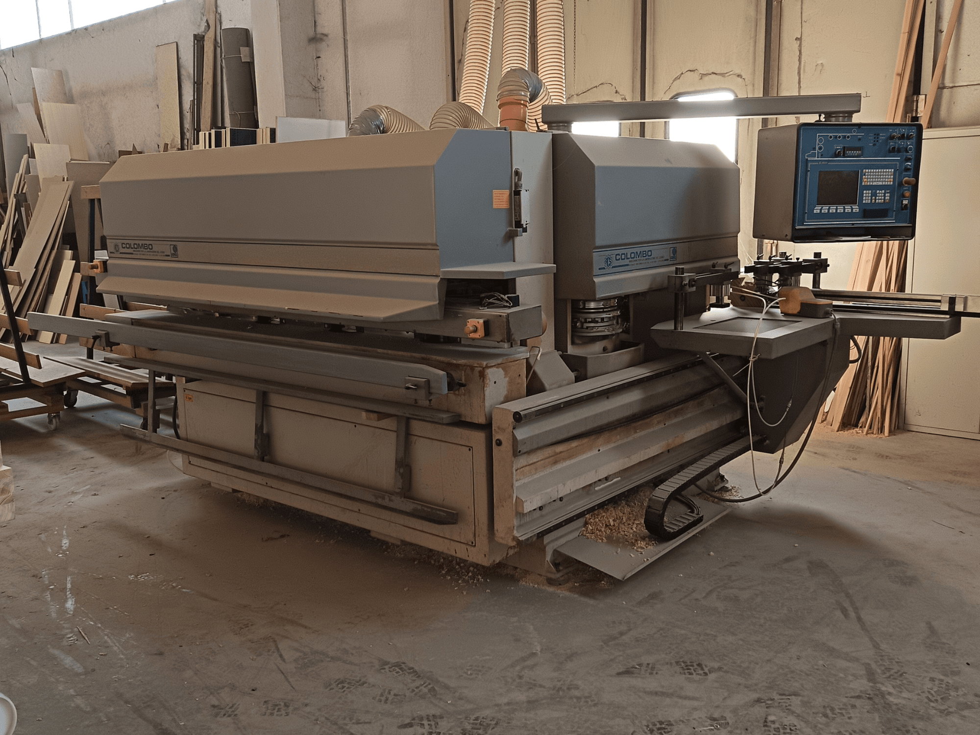 Colombo famegmunkáló gép, oldalnézet, a vezérlőpanel, a vágólemezek és a fűrészpor felhalmozódása a műhelyben.