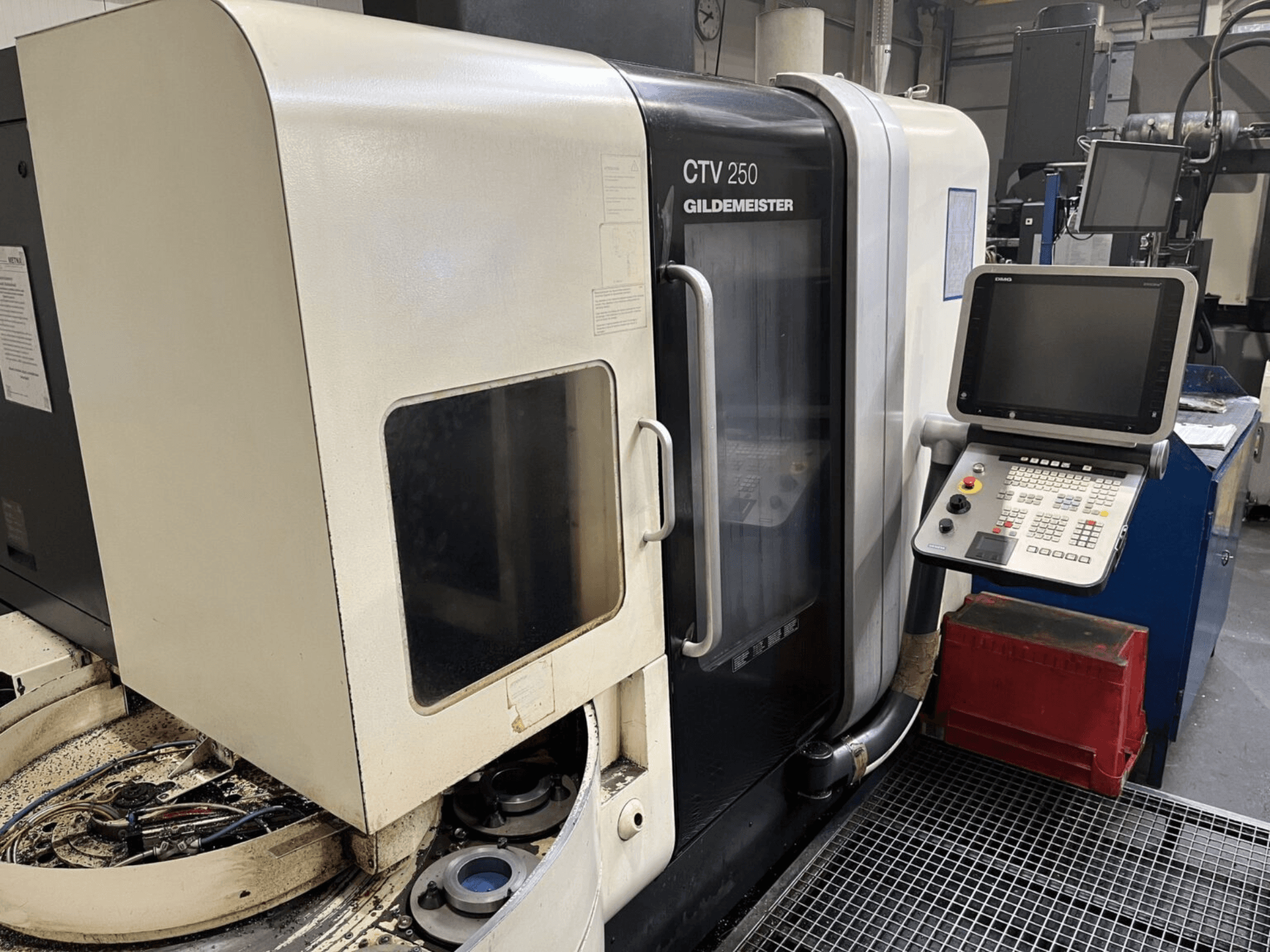 DMG CTV-250 függőleges esztergagép szemből, a vezérlőpanel és a szerszámokkal ellátott munkaterület látható.