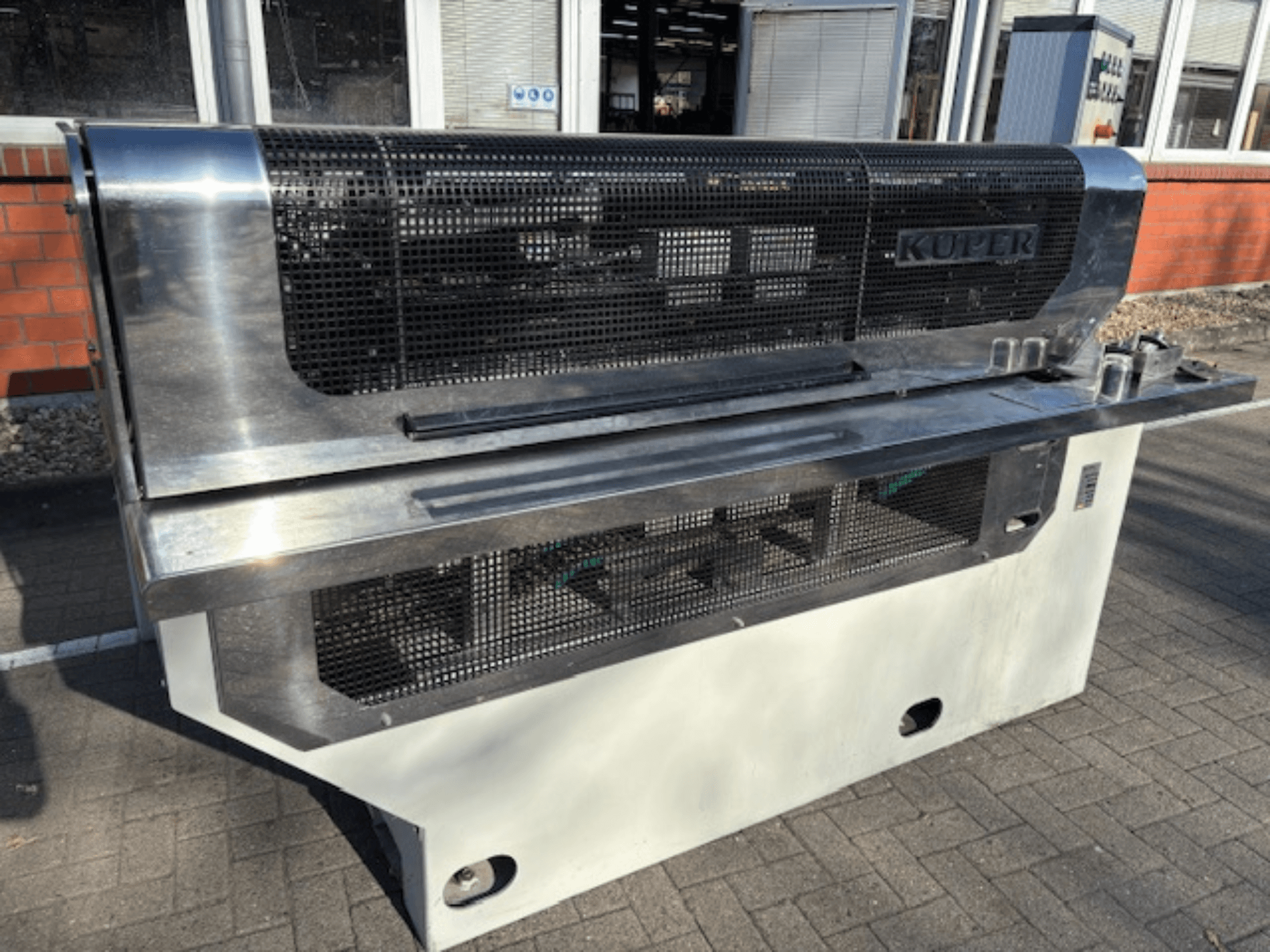 KUPER FLI furnér guillotine, elölnézetben, rozsdamentes acél testtel és védőhálóval a biztonságos működés érdekében.