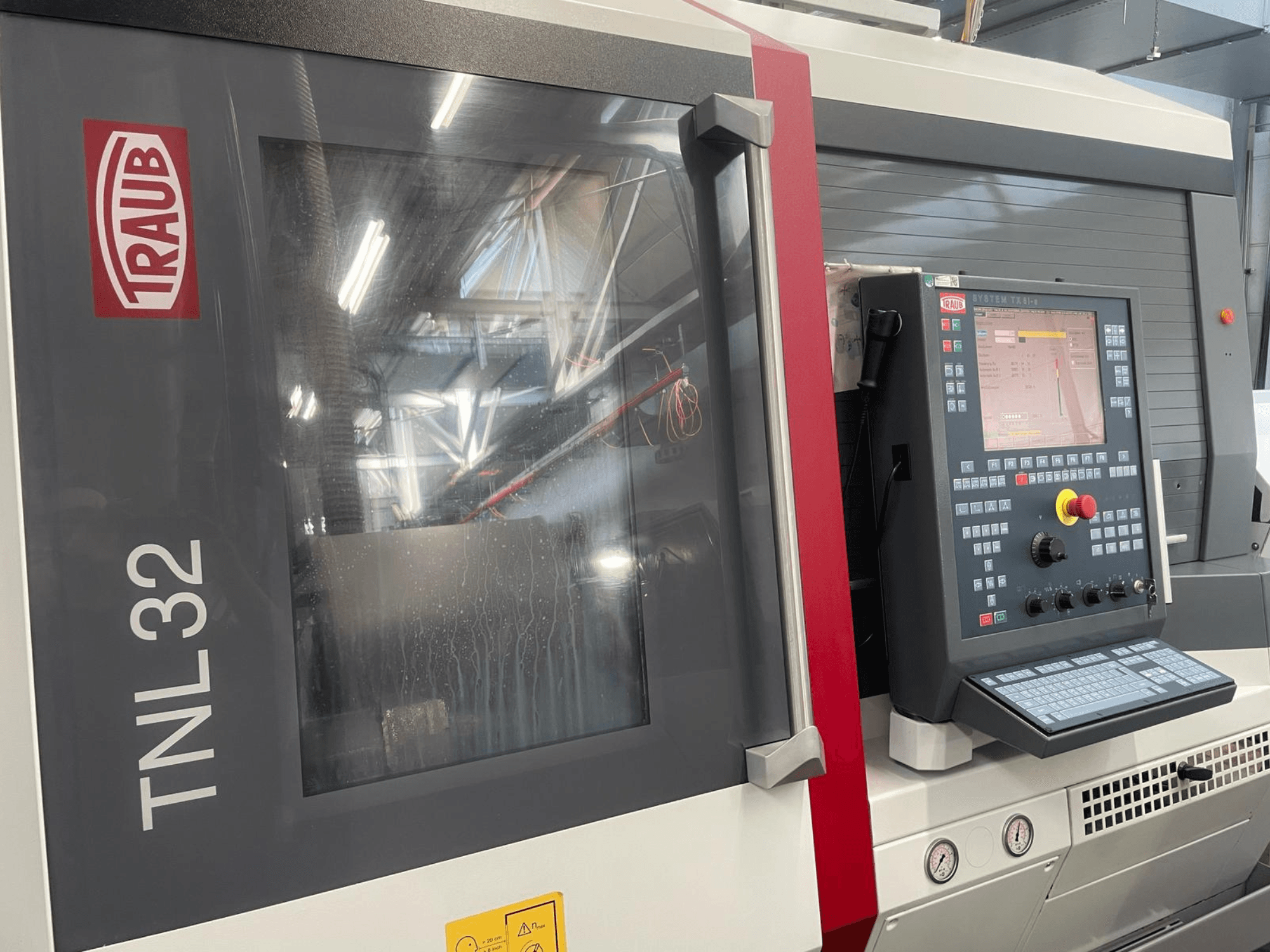 Traub TNL32 CNC eszterga előlapja, a gombokkal ellátott vezérlőpanel, a kijelző képernyő és a karcsú fémház.