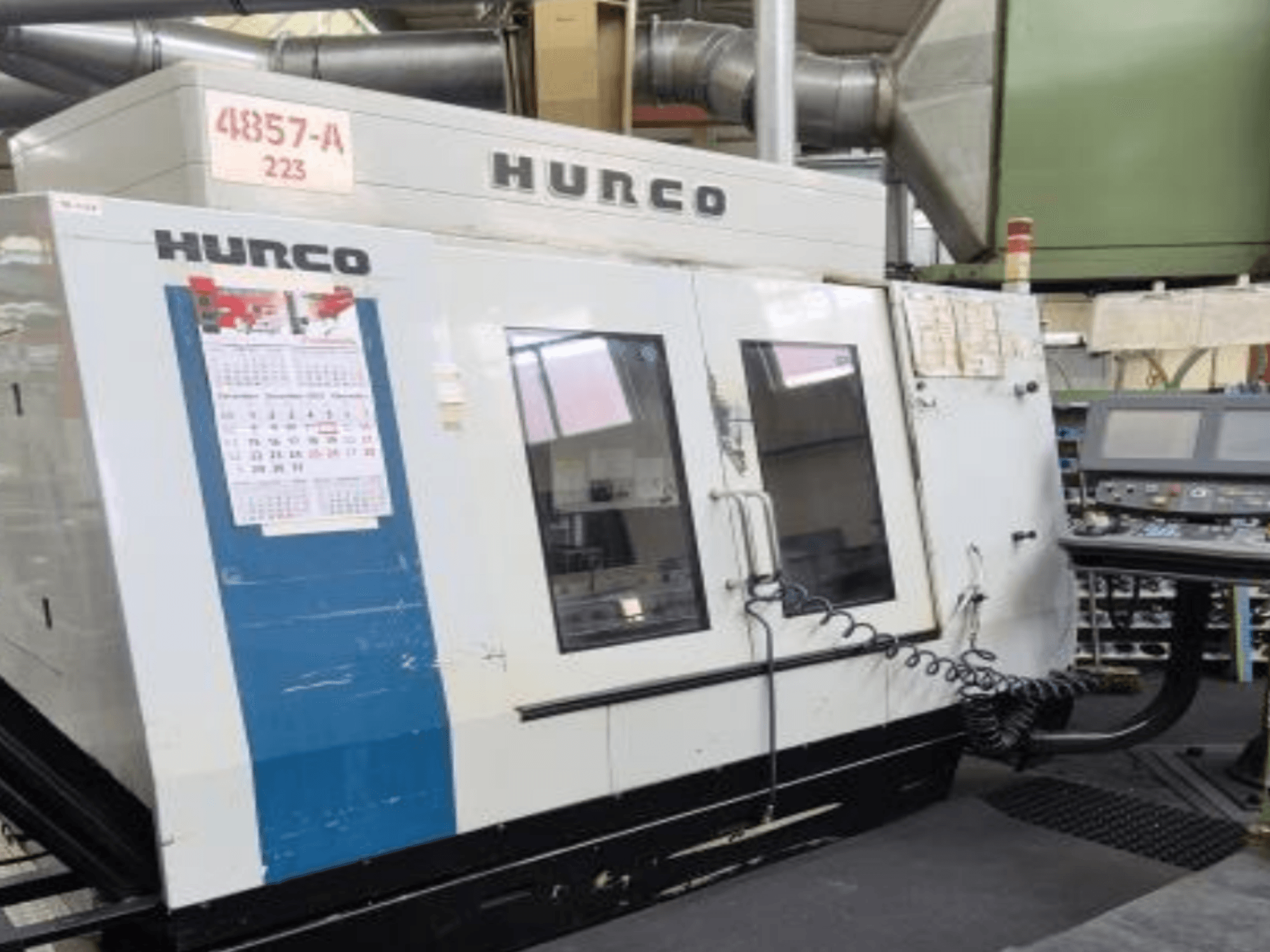 Hurco VMX 42 függőleges megmunkálóközpont elölnézetben, vezérlőpanel, naptár és fém külső részletek.