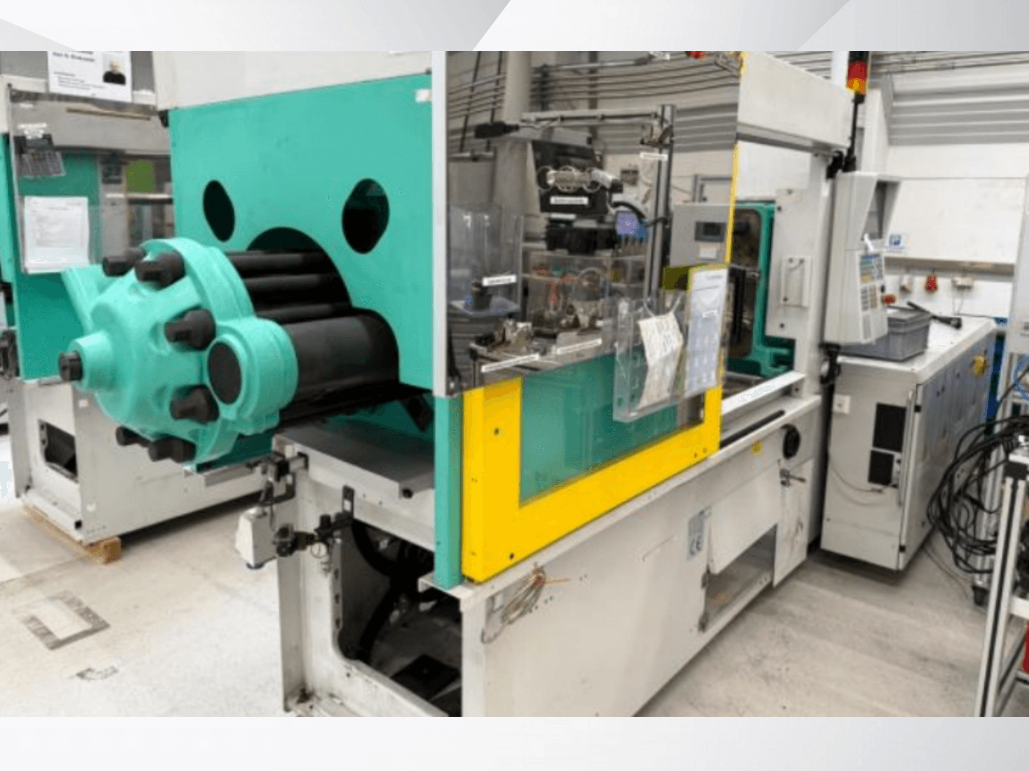 Világoskék és sárga színű fröccsöntőgép, elölnézetben, látható szerszámmal és címkékkel ellátott vezérlőpanellel.