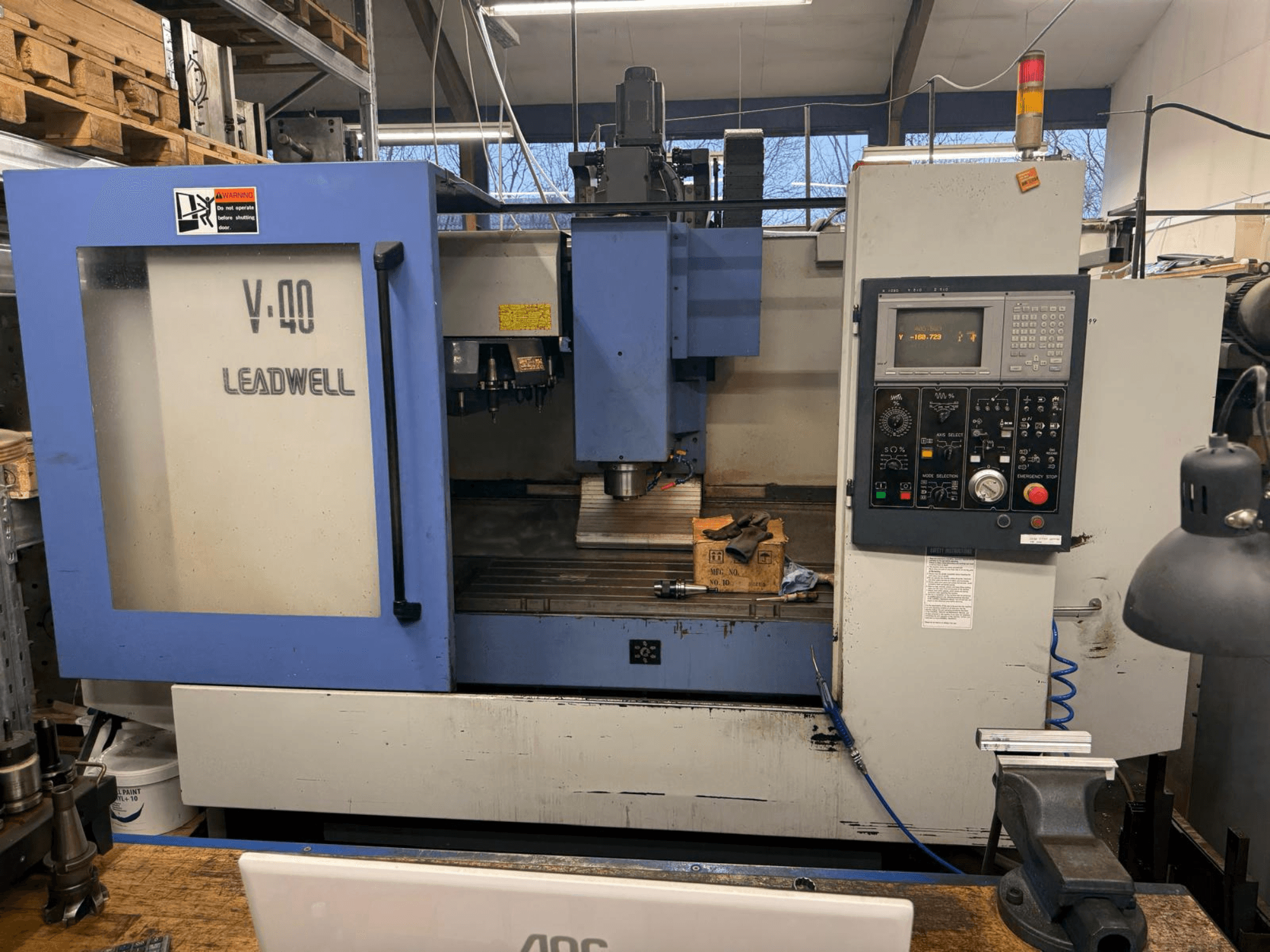 LEADWELL V-40 CNC marógép, elölnézet, vezérlőpanel, vágószerszámok és egy csőváz egy munkapadon.